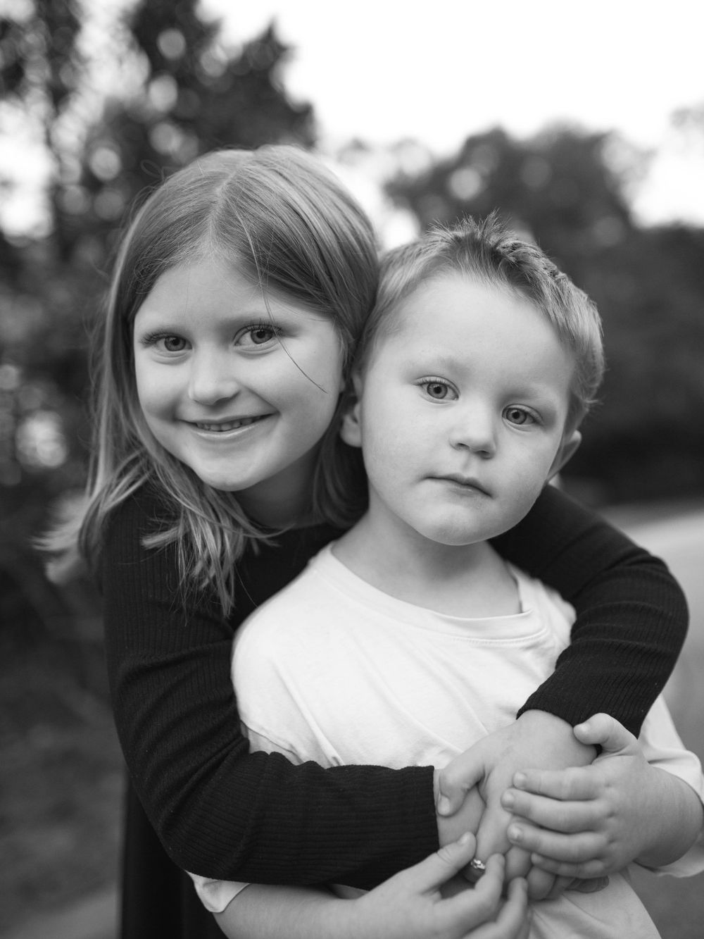 A black and white portrait by B. Logsdon Photography of Bluffton, South Carolina shows a brother and sister embracing.