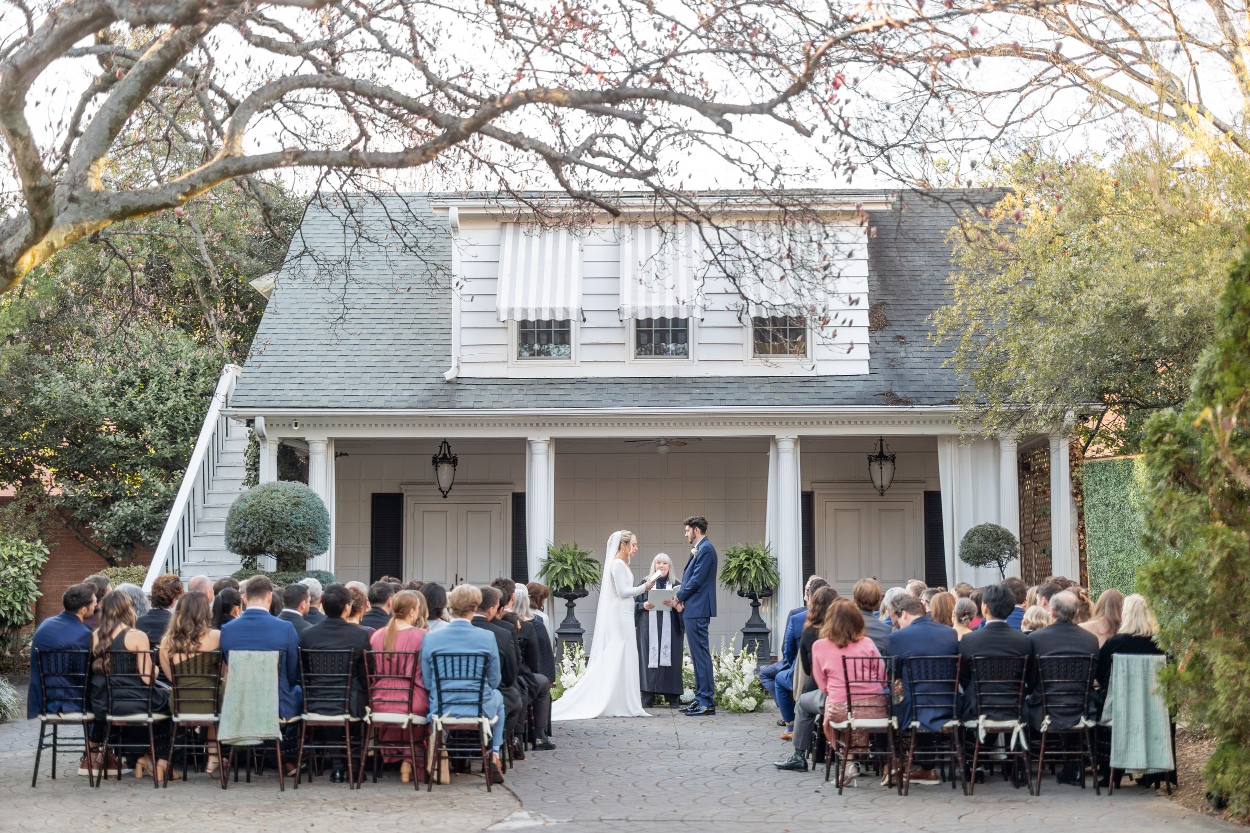 A panoramic view of an outdoor wedding ceremony setup with chairs and decorations in a garden setting.