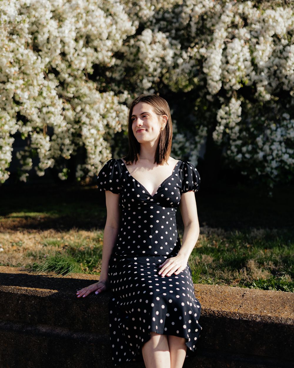 Portrait session against blooming white spring flowers at sunset.