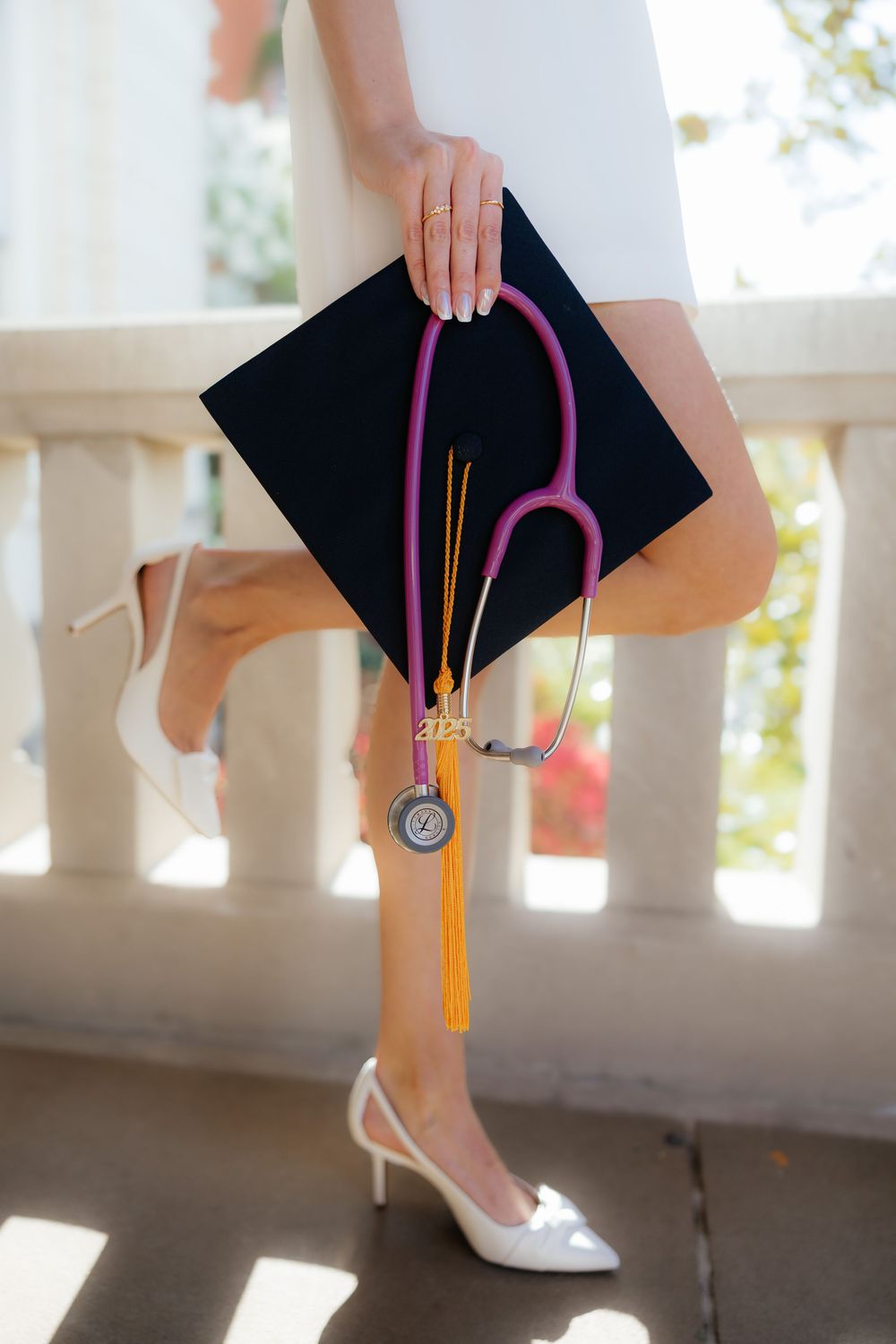 Close-up of graduation cap and tassel details against white railing.