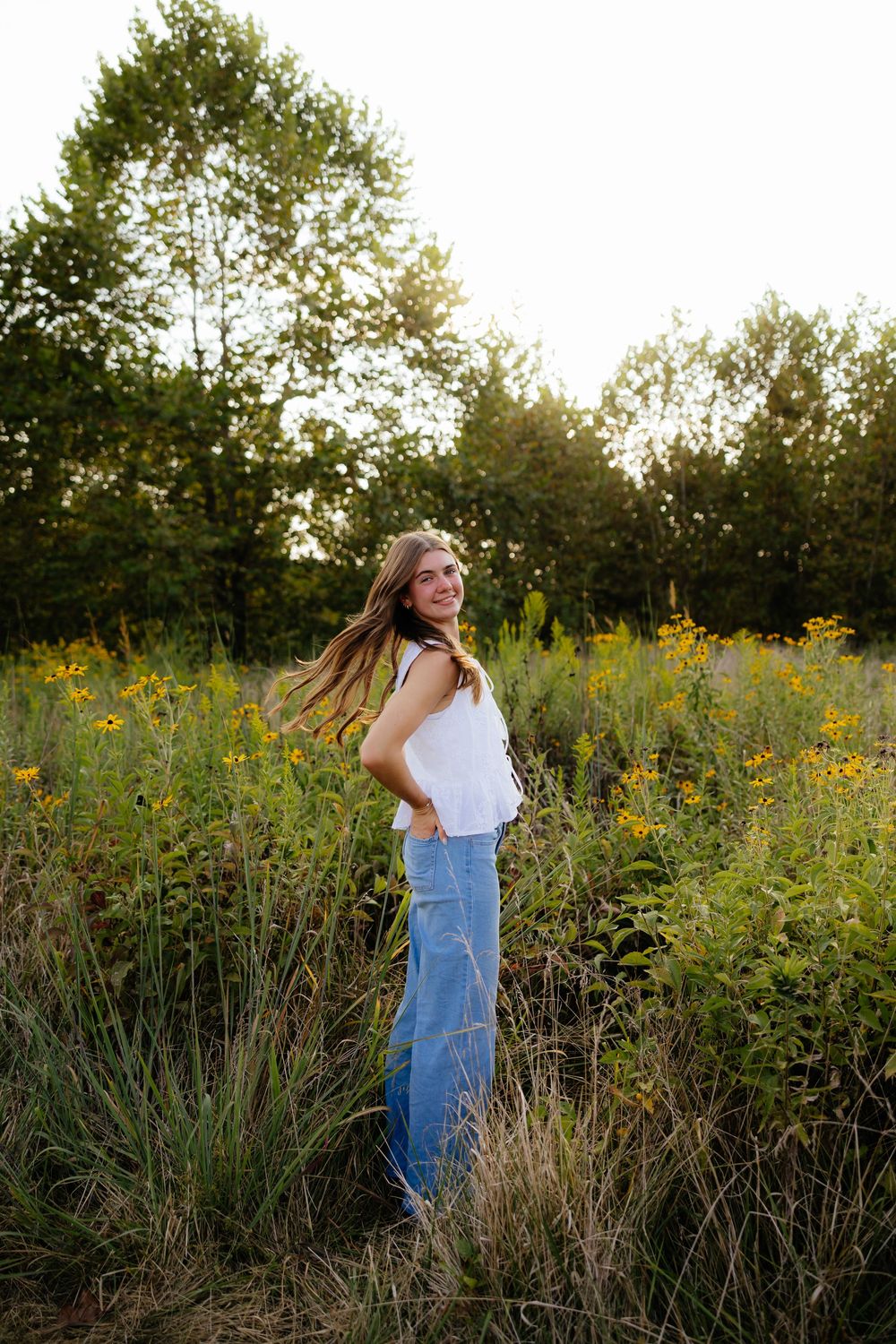 Candid portrait session in field of yellow wildflowers during golden hour sunset.