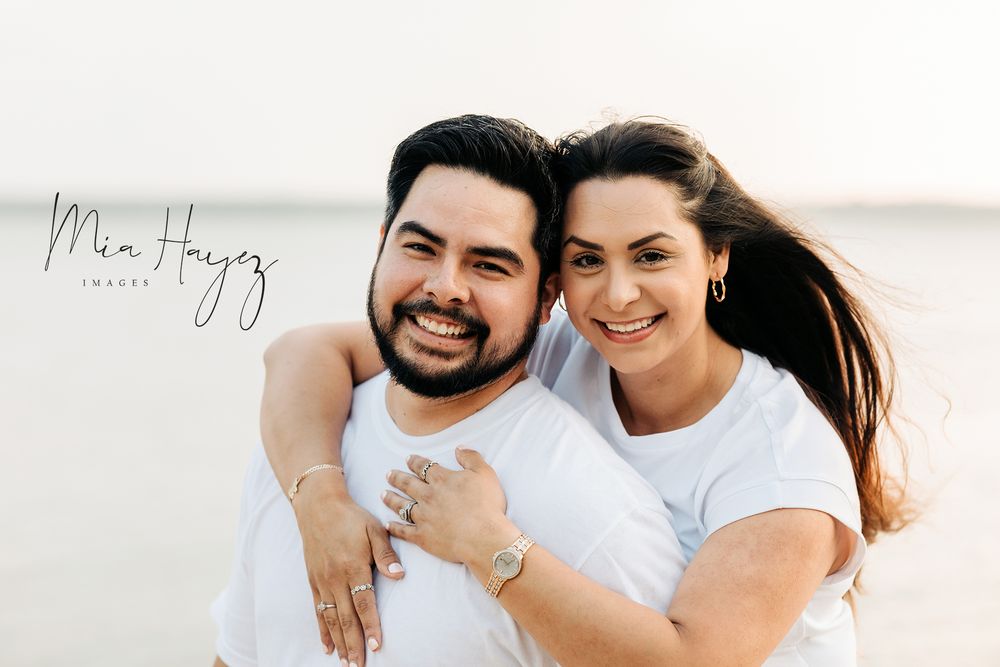Couple in white outfits embracing during outdoor photo session.