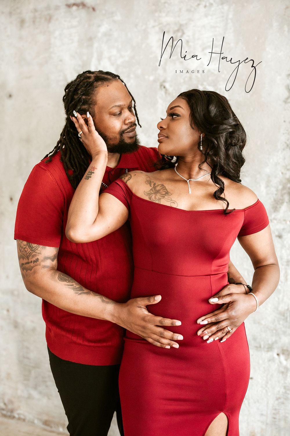 Maternity photoshoot featuring a couple in red and black attire showing loving embraces.