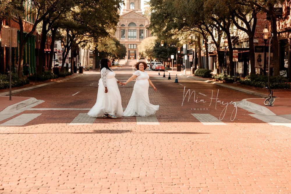 Wedding couple walking through a tree-lined city street in formal attire.