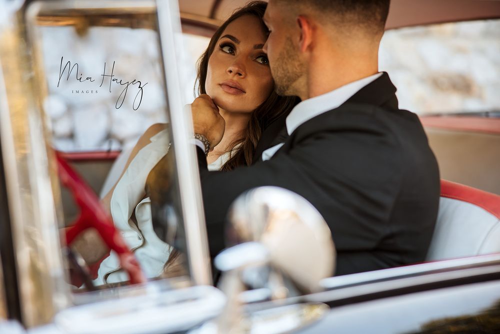 Romantic car photoshoot with couple sharing intimate moments in formal attire.