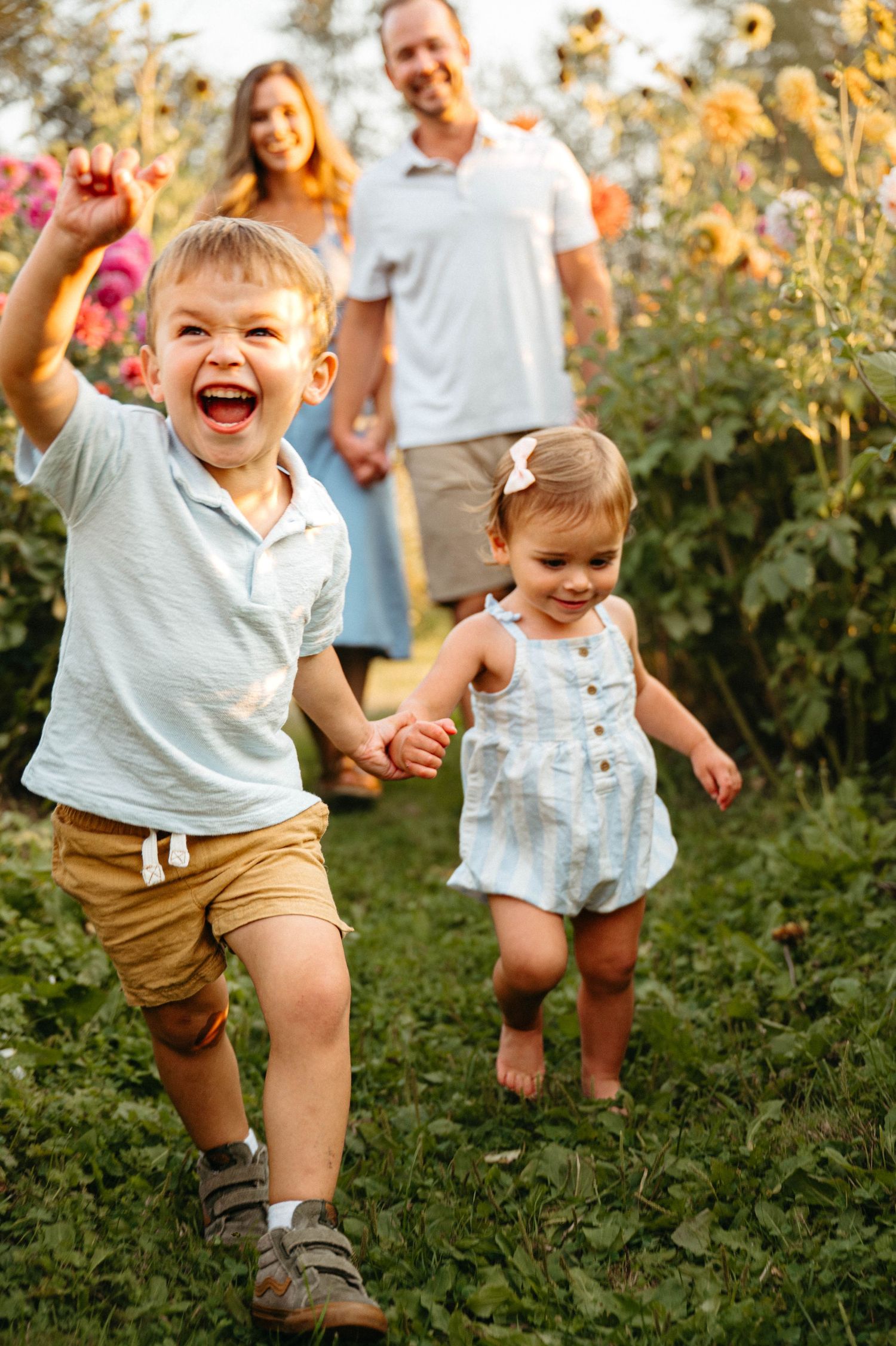 Children playing and running through a garden filled with flowers at sunset.
