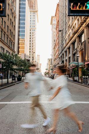 Engaged couple running across street in downtown. Cincinnati Wedding photographer. NKY wedding photographer. Chicago Wedding Photographer.