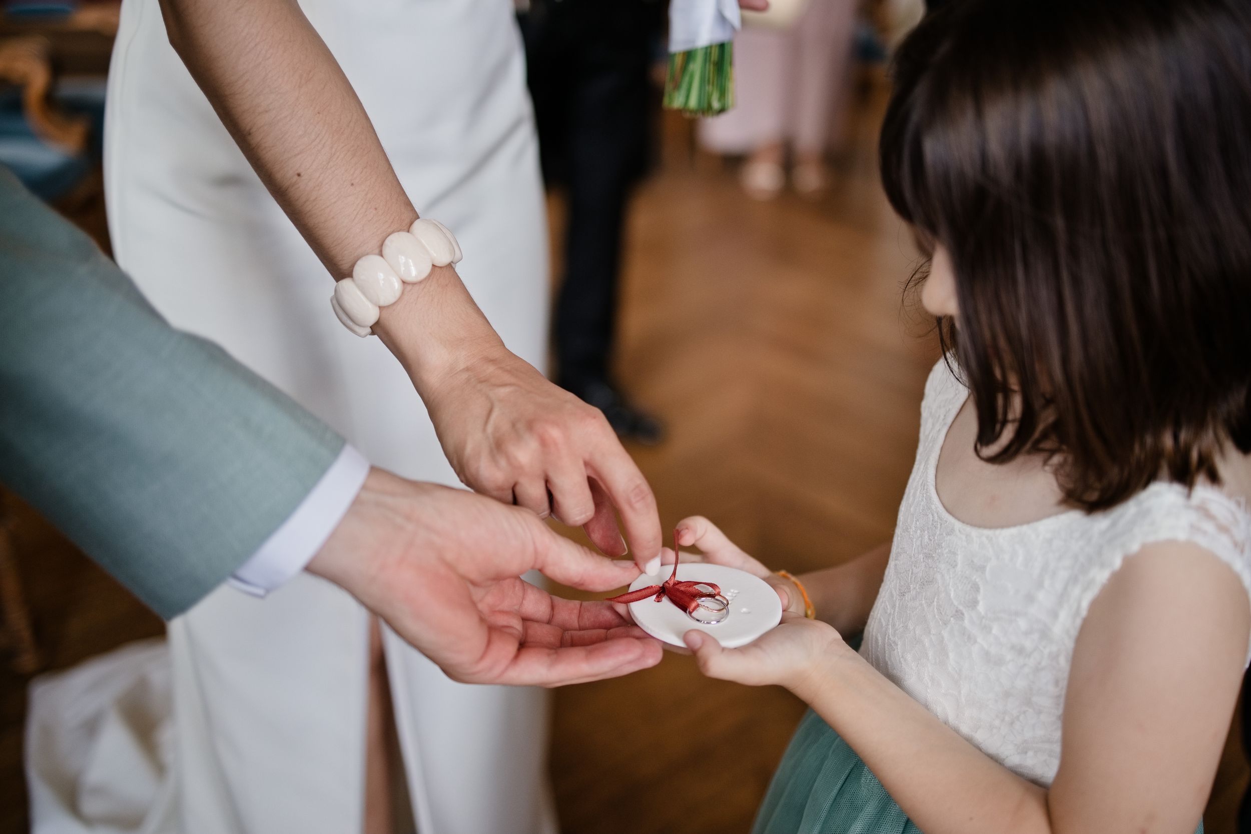 Petite fille apportant les alliances aux mariés, gros plan sur leurs mains