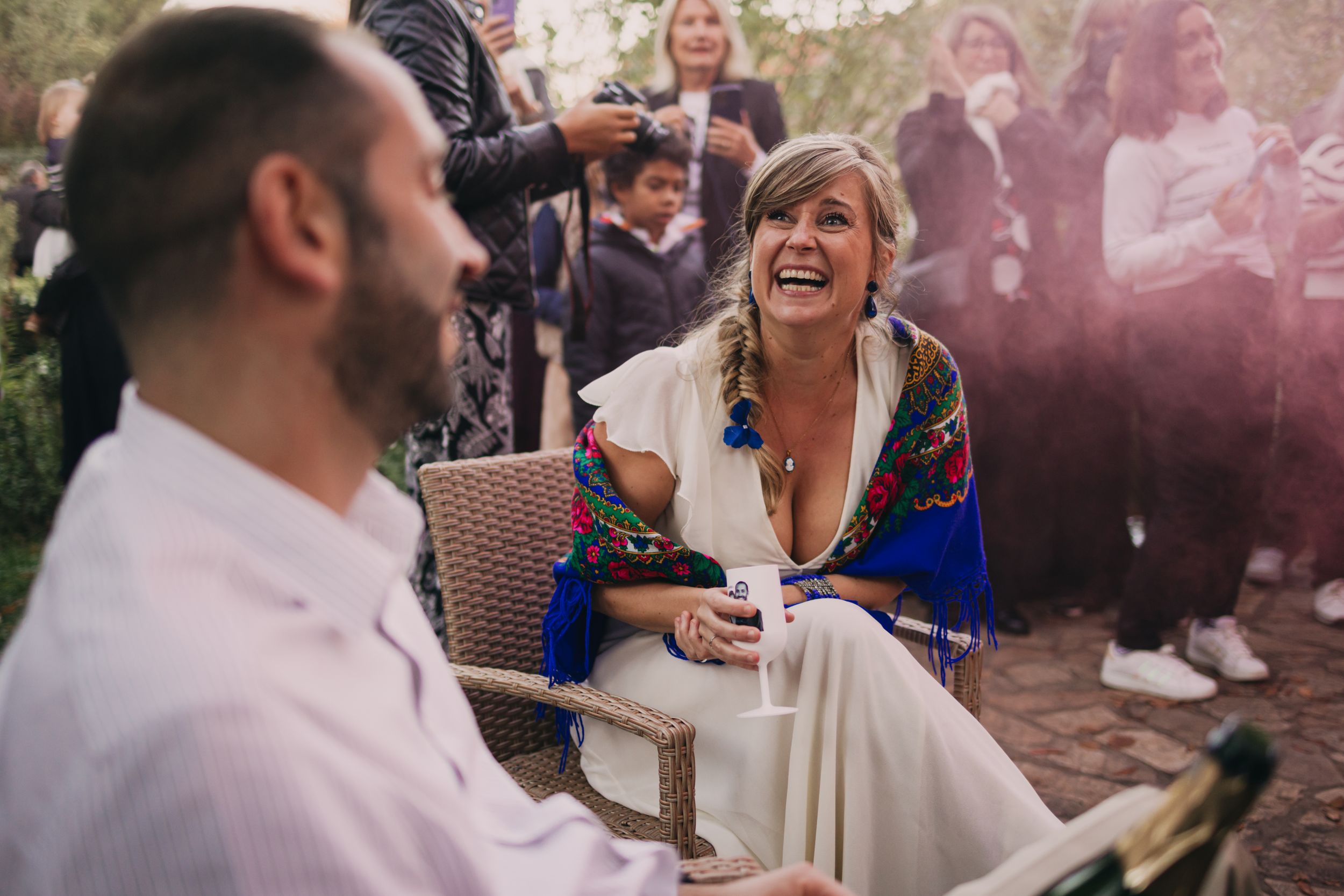 Des mariés rient aux éclats pendant un jeu organisé par leurs invités. L'ambiance est festive et la photo plongée dans la lumière rosée