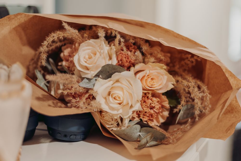 Peach and pink roses wrapped in brown kraft paper creating an elegant bouquet.