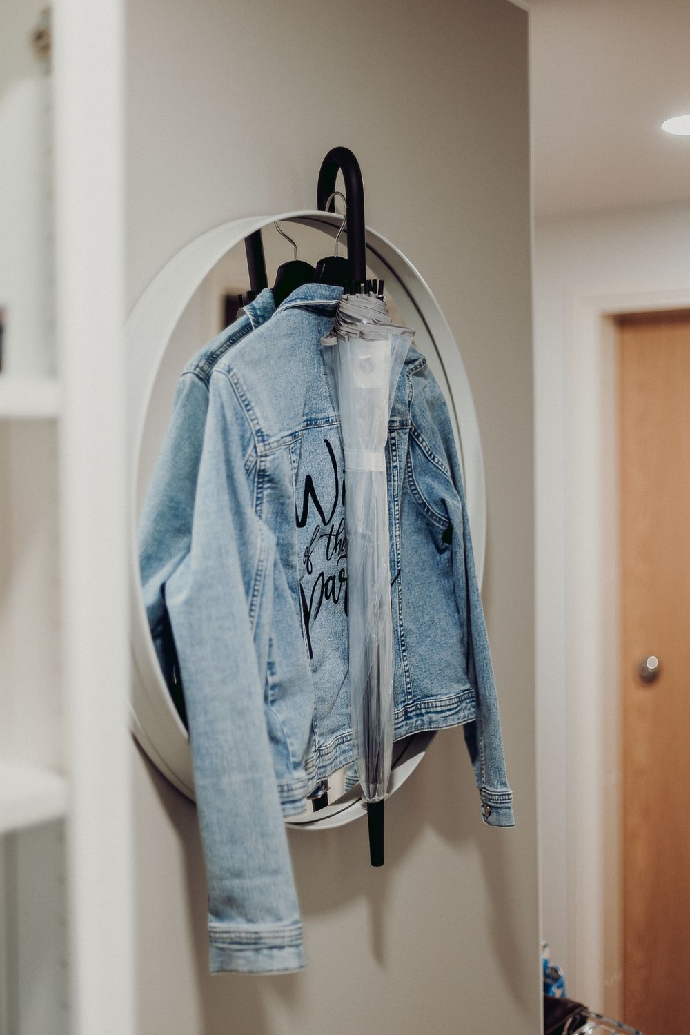 Light blue denim jacket hanging on display against a white wall.