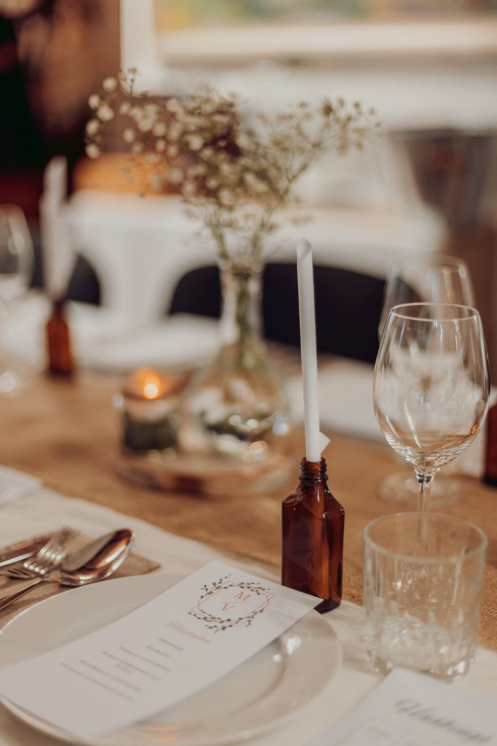 Wedding reception table with place settings, wine glasses, and delicate floral centerpieces.