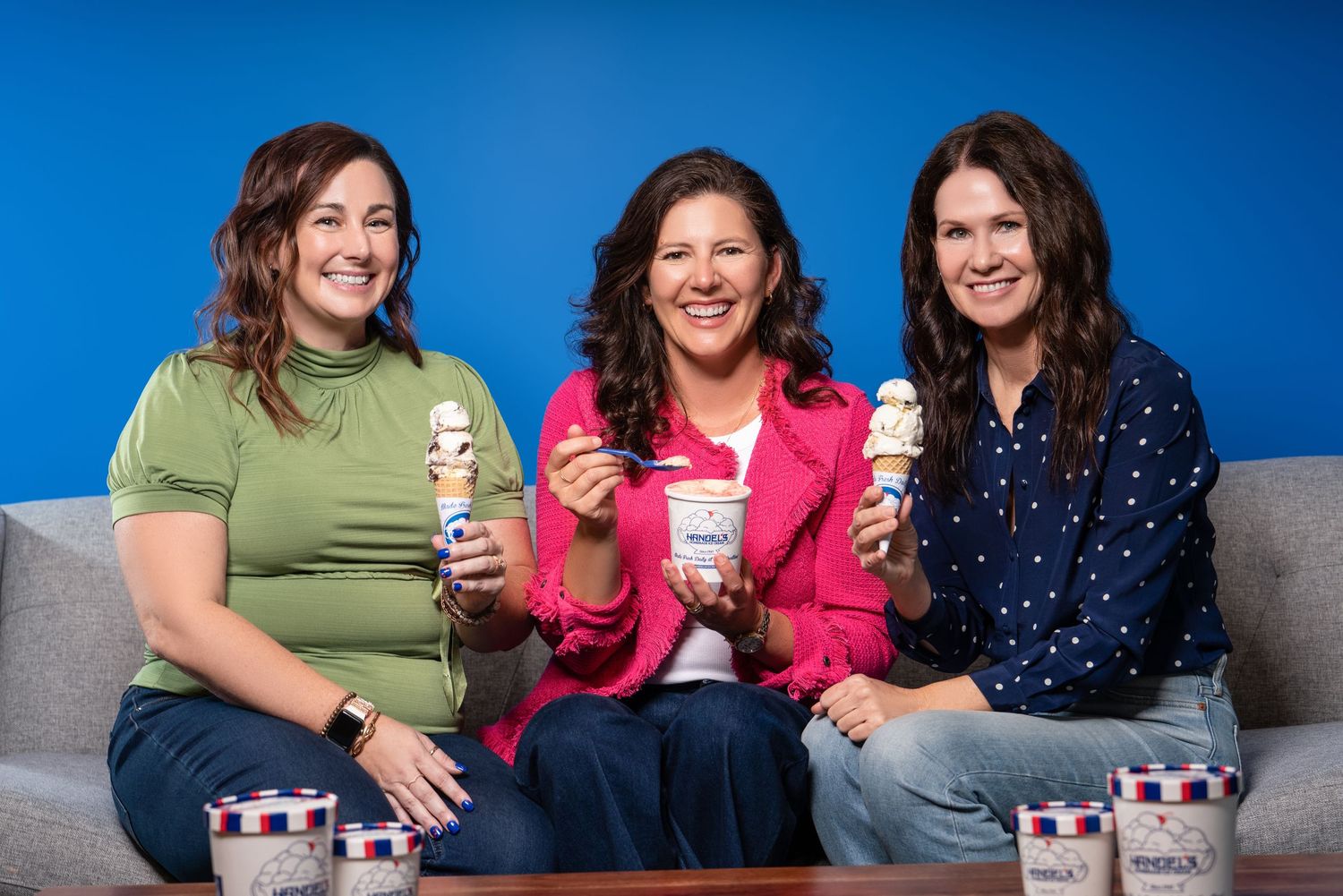 Three people sitting on couch enjoying ice cream together.