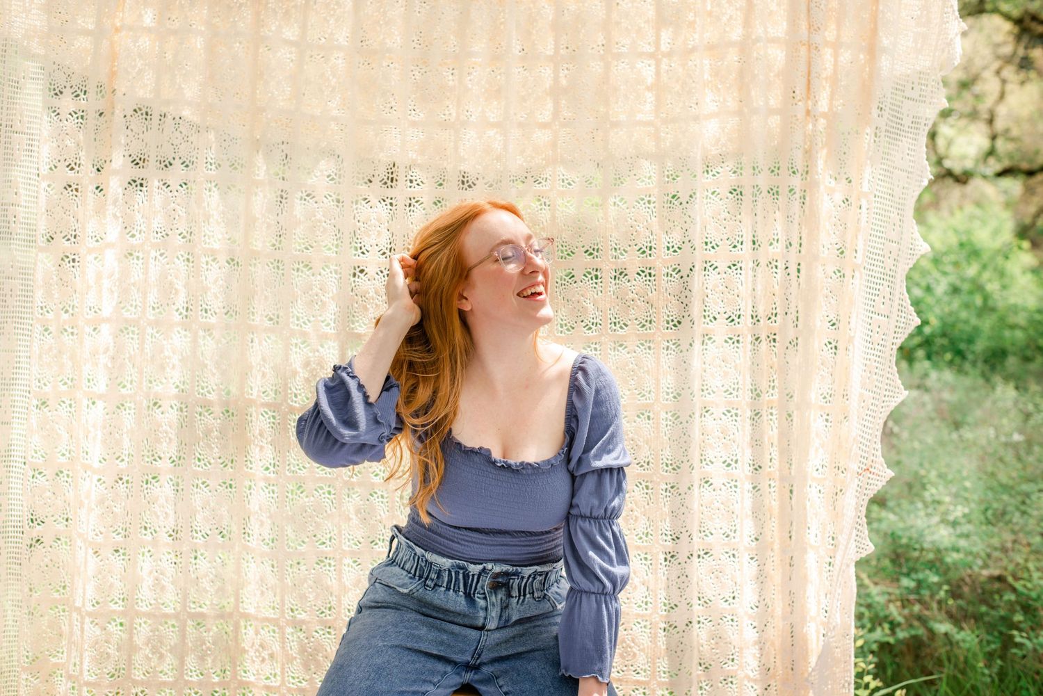 Artistic portrait with model in blue top against cream colored lace background.