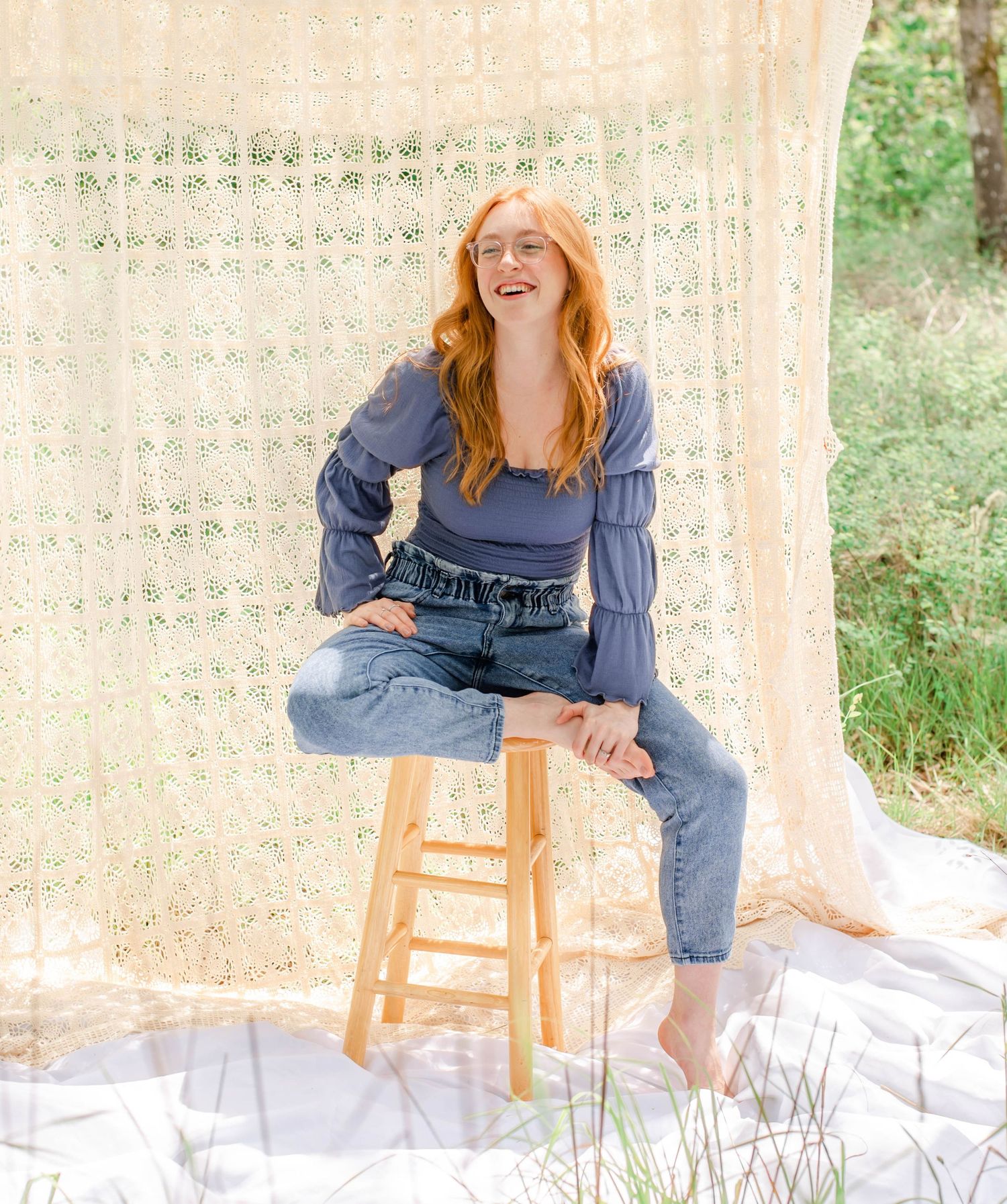 Casual portrait session with subject in denim against white lace backdrop outdoors.