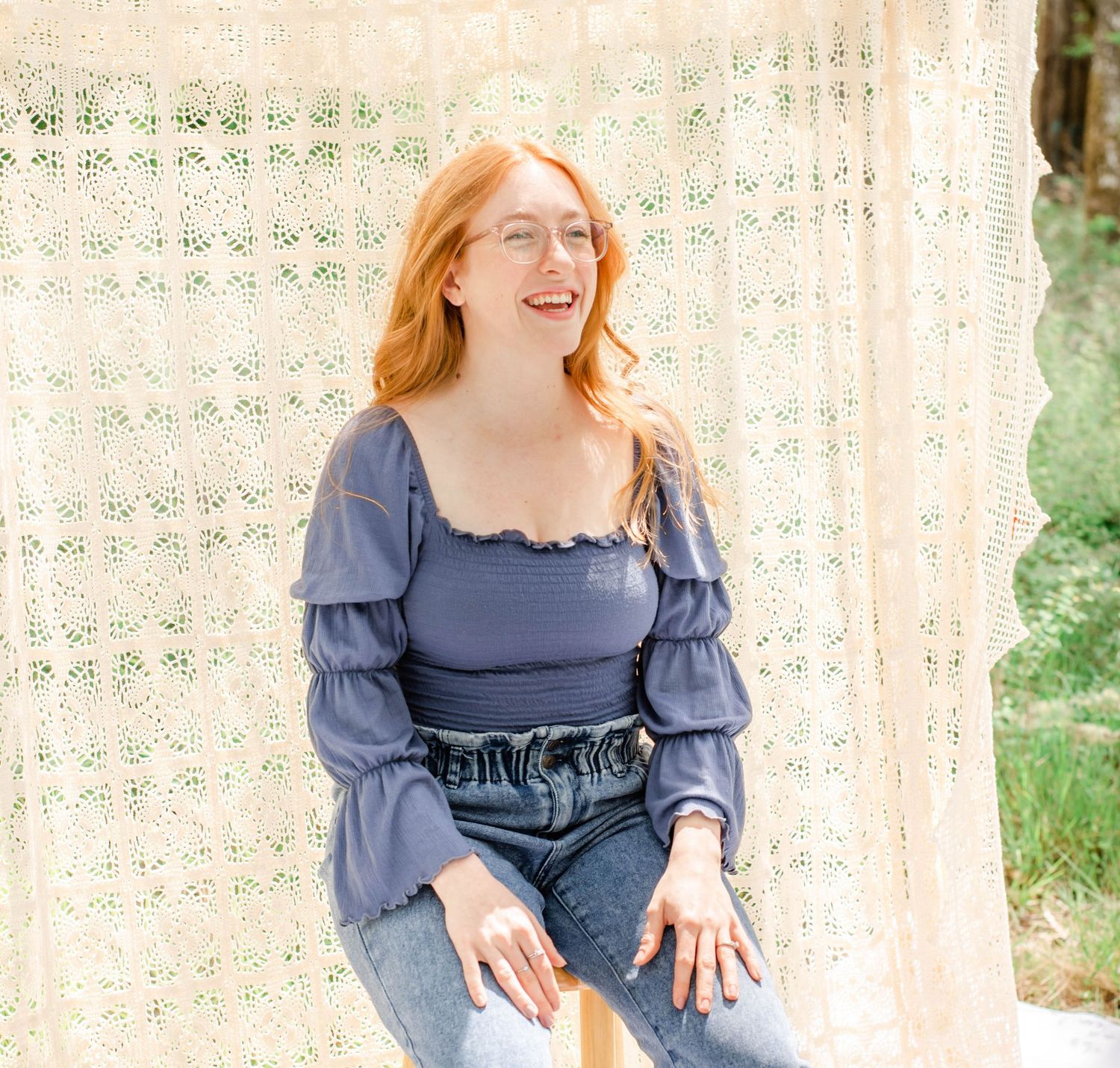 Dreamy outdoor portrait with blue peasant top and denim against cream lace backdrop in natural lighting.