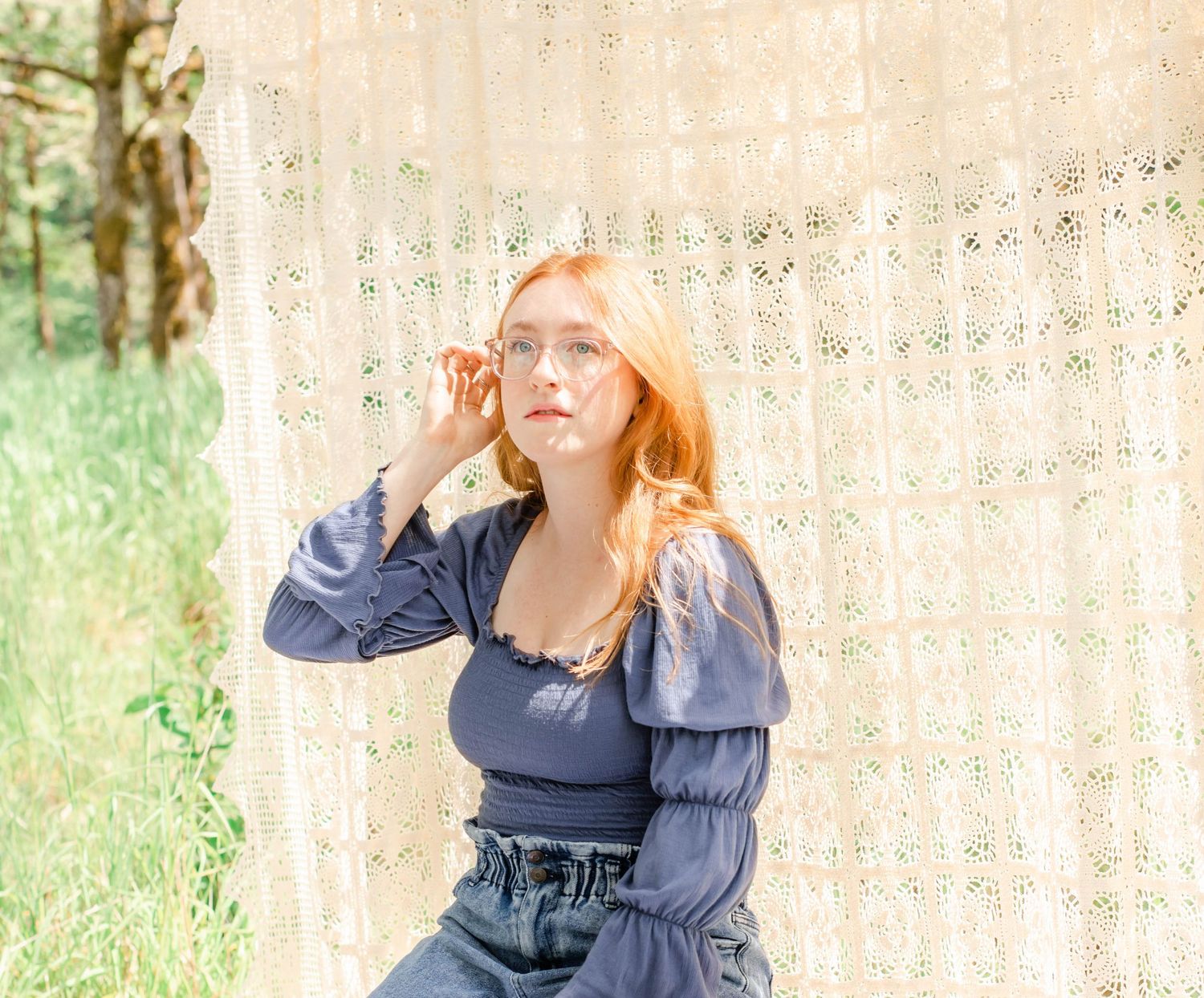 Ethereal portrait against cream lace curtain with soft natural lighting and blue peasant blouse.