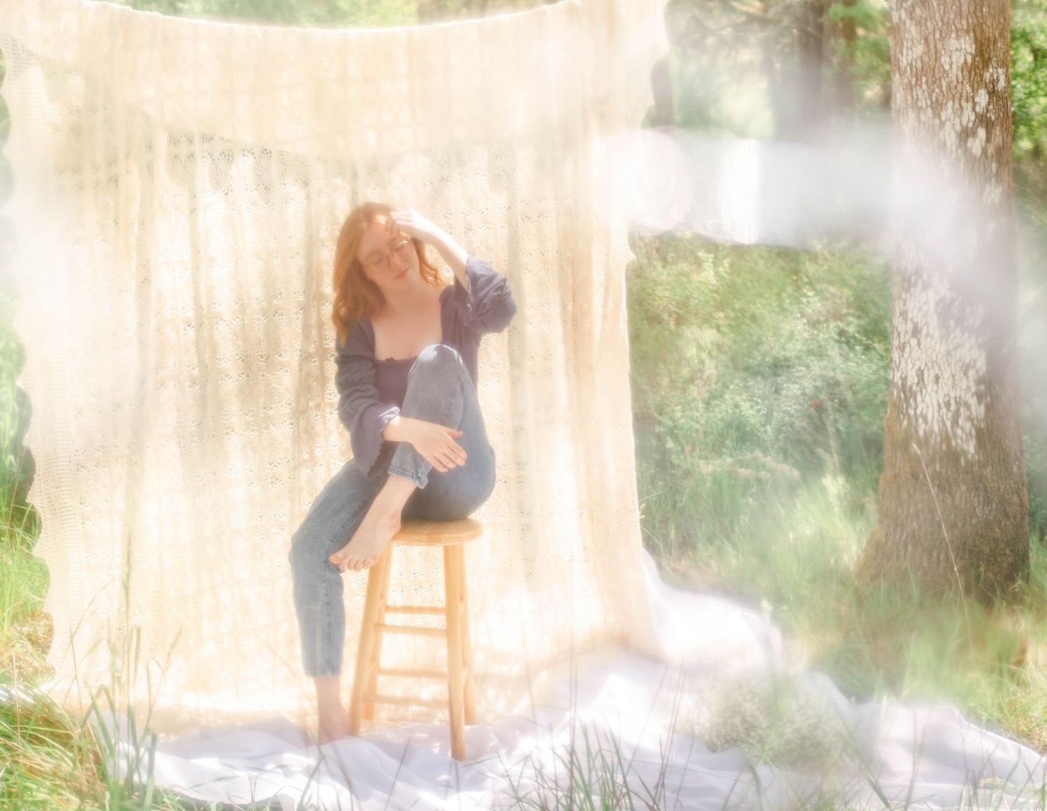 Artistic portrait on wooden stool with dreamy smoke effects and natural backdrop.