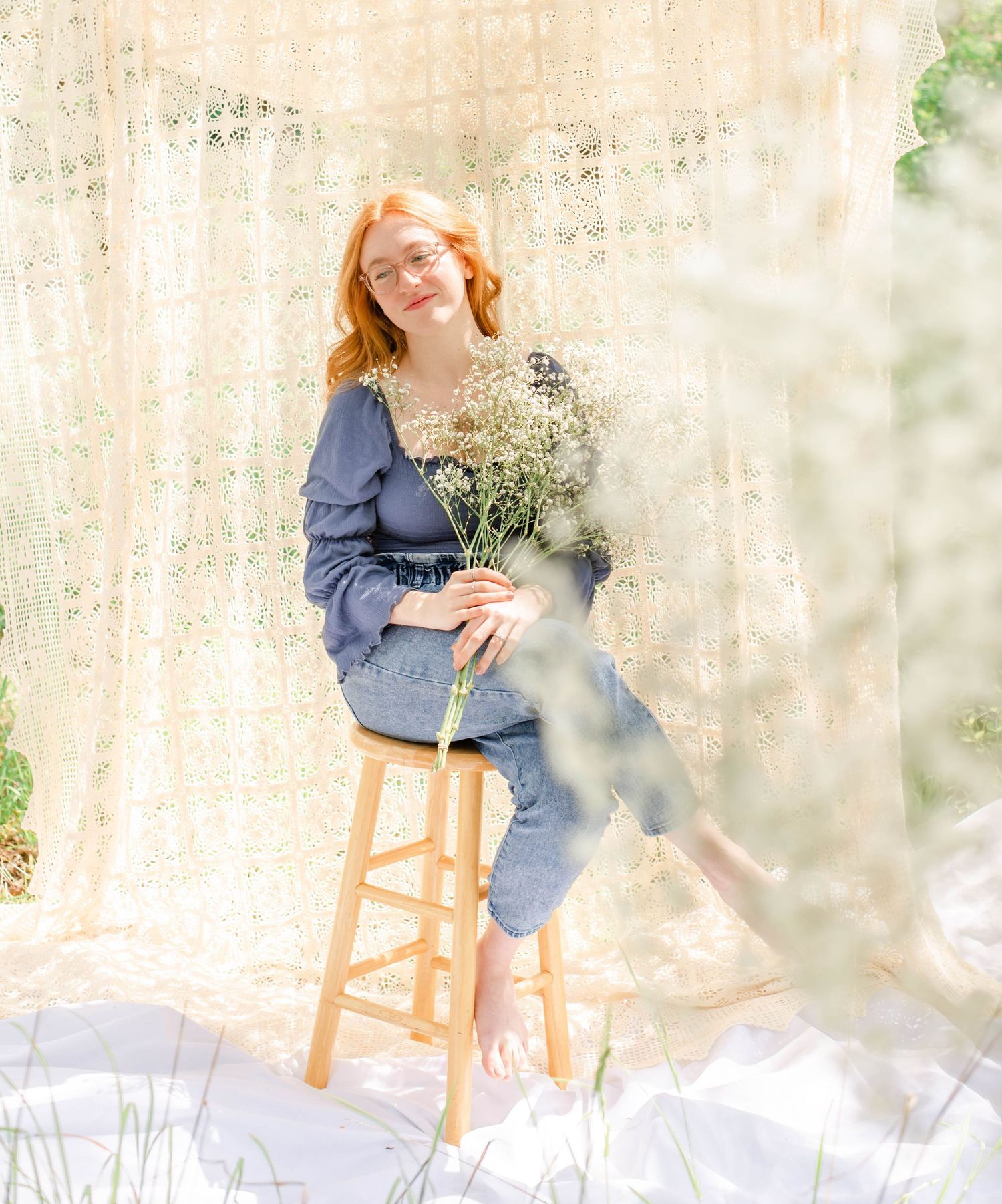 Romantic outdoor photo with baby's breath flowers against lace curtain backdrop.