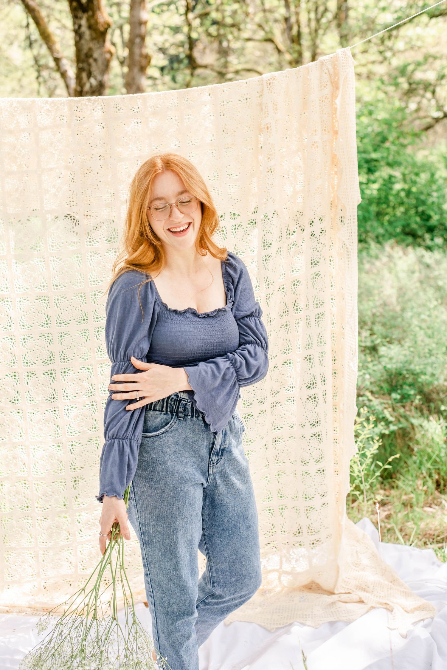 Casual outdoor portrait in denim and blue top with delicate lace background.