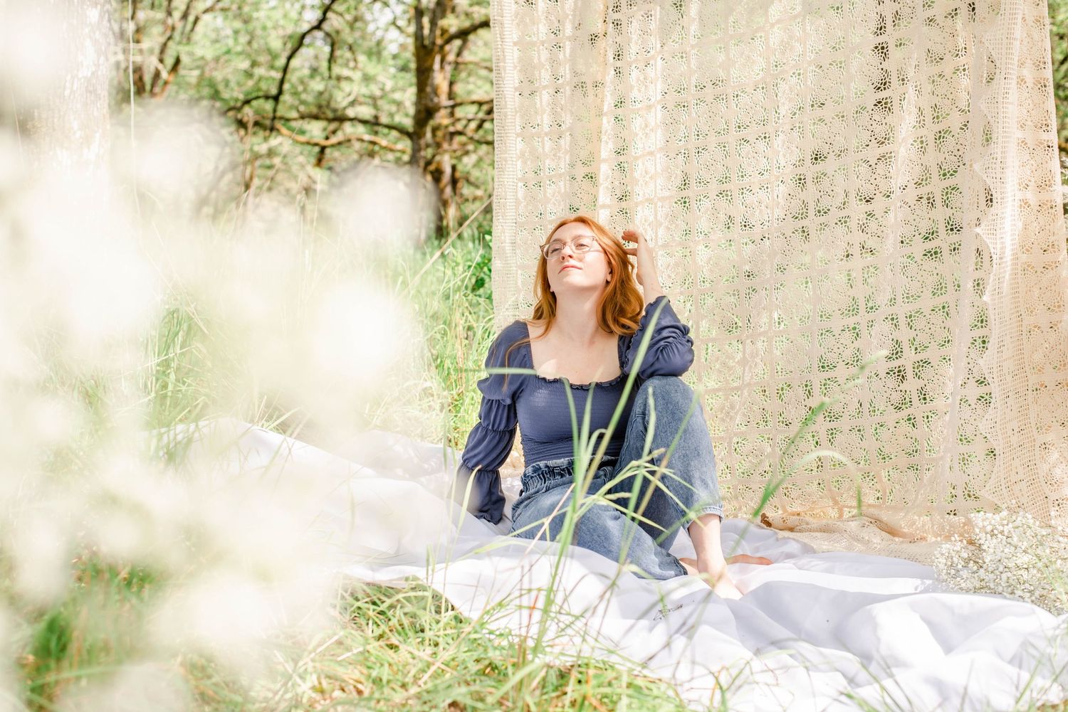 Person relaxes on white blanket during outdoor portrait session with natural lighting.