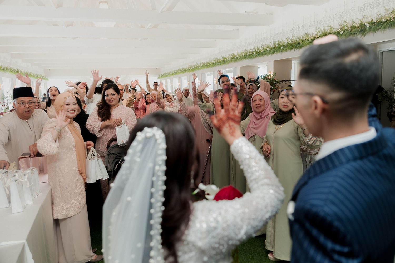 A group of wedding guests celebrate and cheer during a reception.