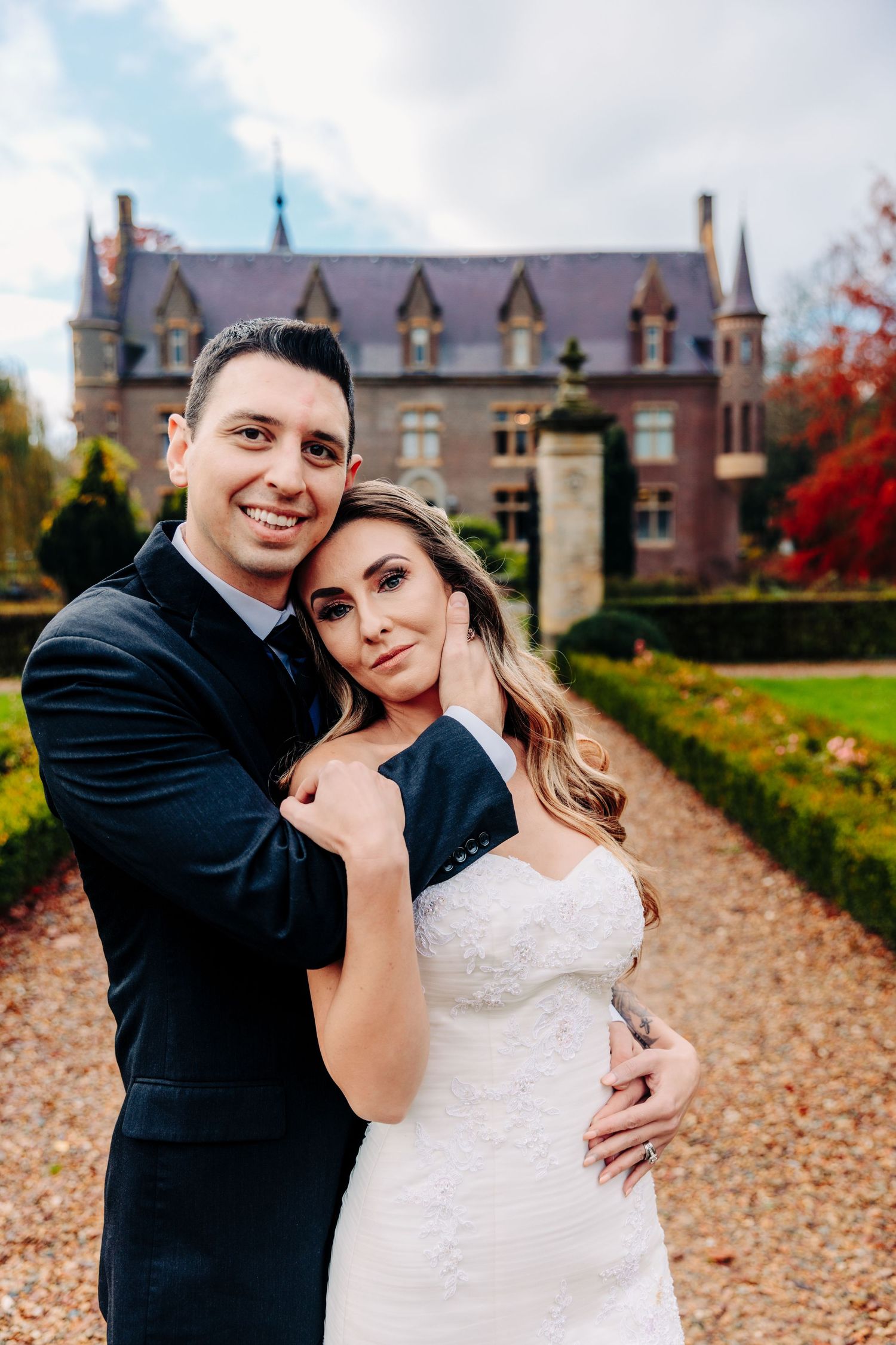 A joyful wedding portrait of a couple embracing on the grounds of a historic castle during autumn.