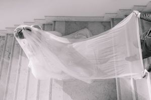 Black and white photo of a flowing white wedding veil billowing in the wind against marble columns.
