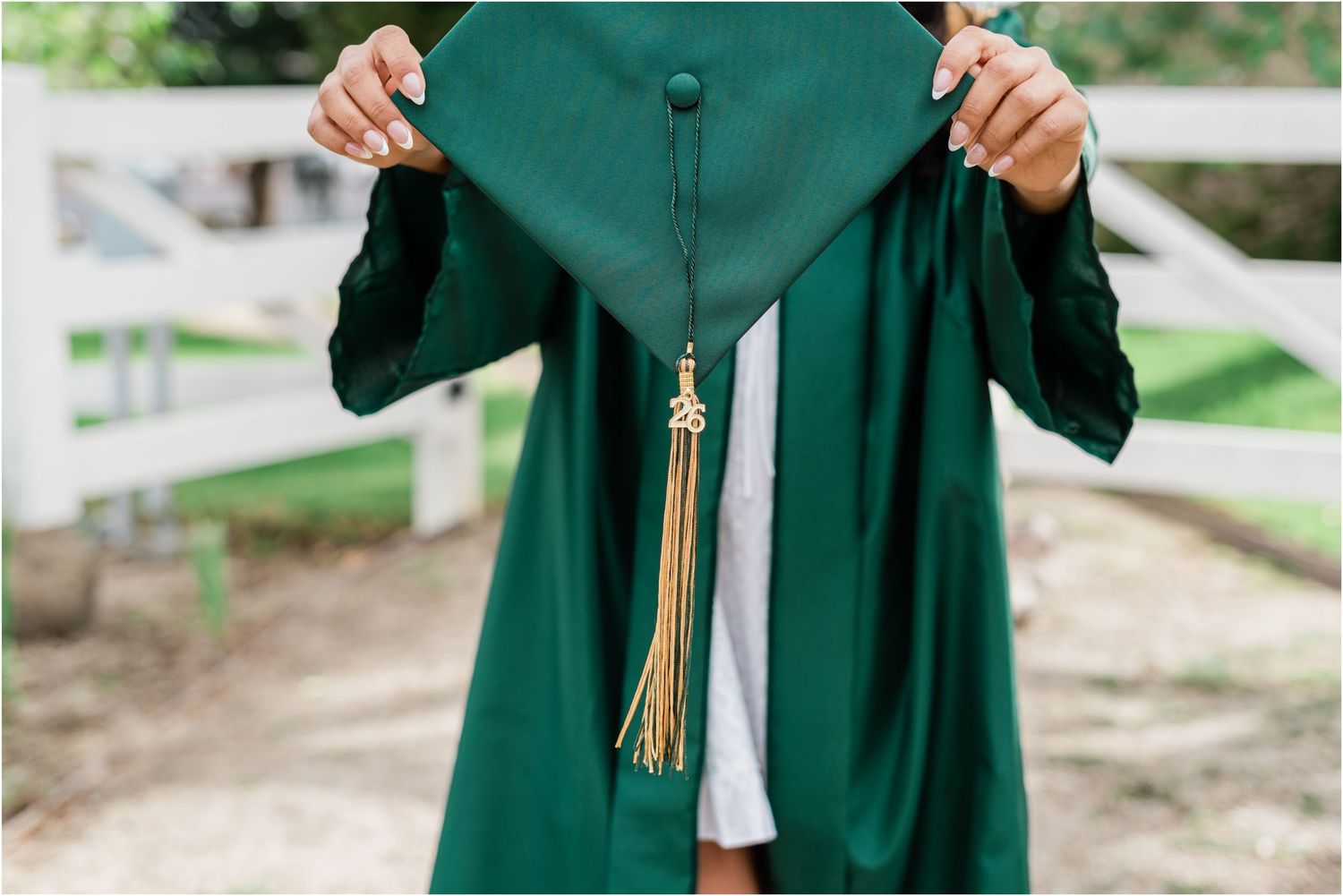 High school senior holding cap during her senior photo session at Madonna Inn Gardens in San Luis Obispo for cap & gown senior photos