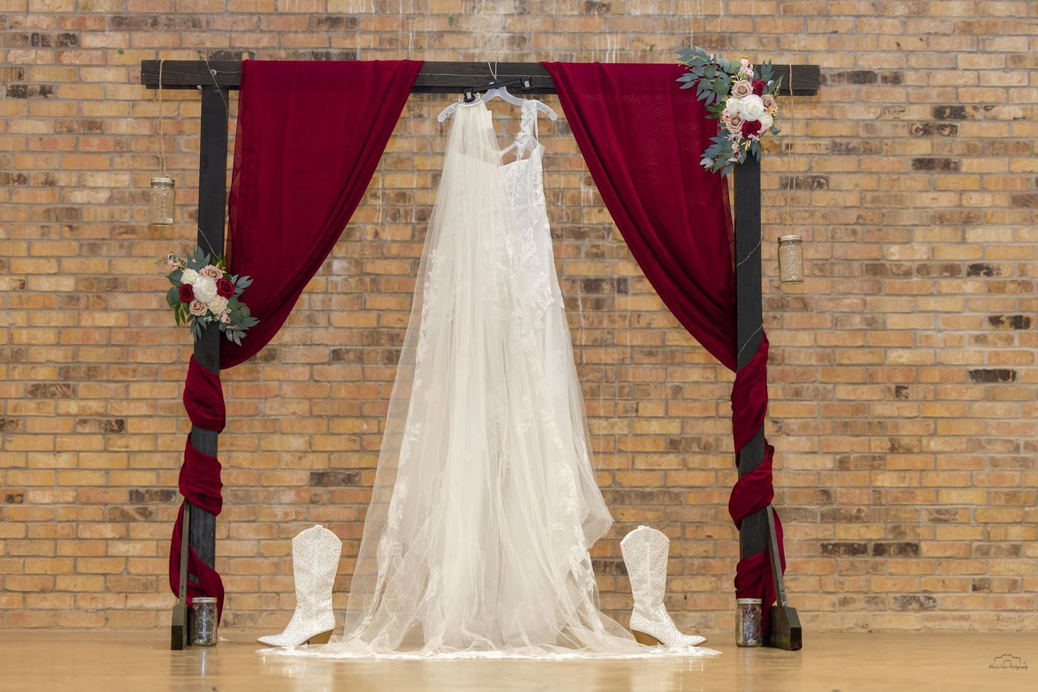 Elegant lace wedding gown with floral appliques and cathedral train hanging on a door in a sunlit room.