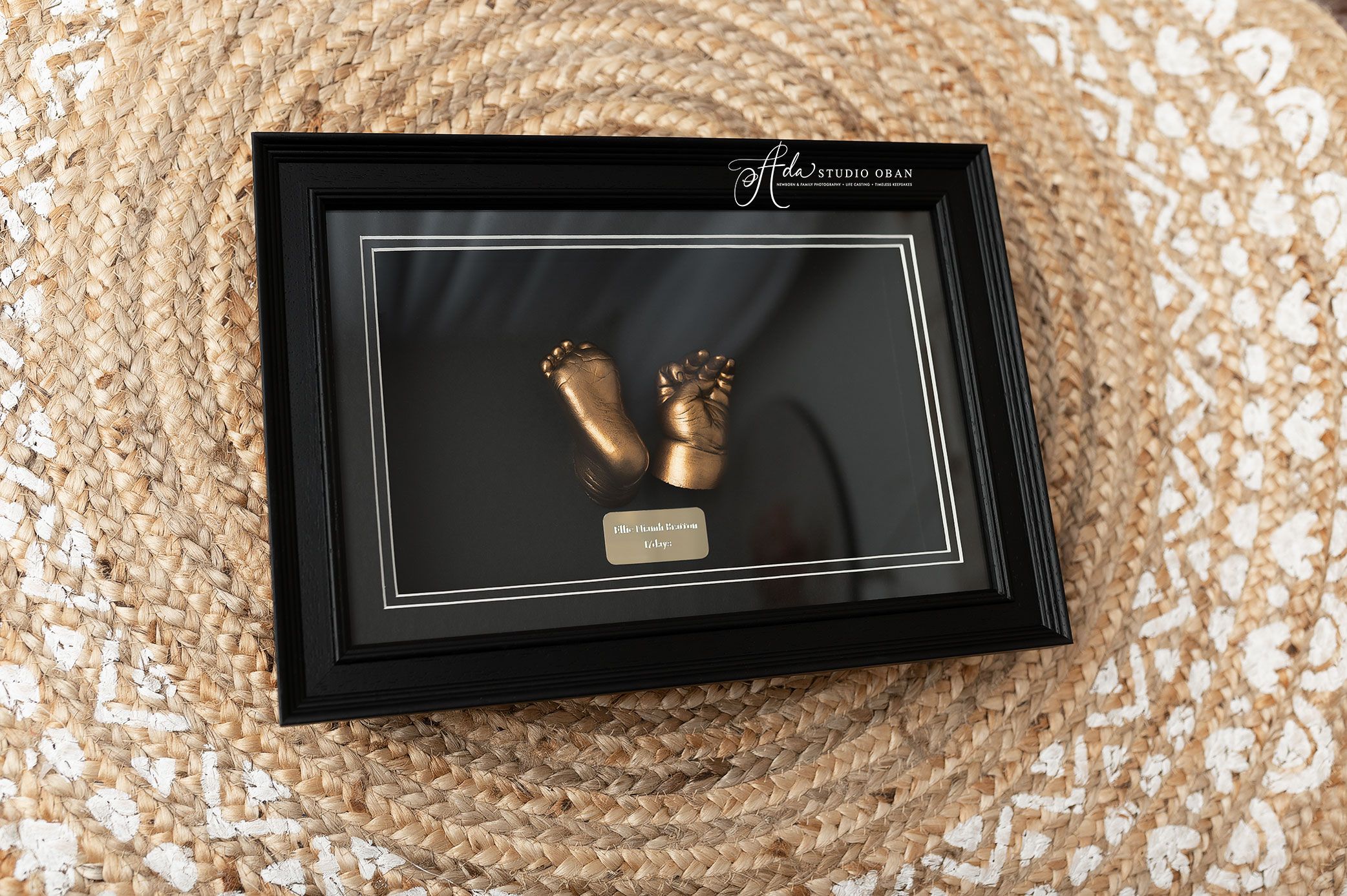 Framed 3D bronze baby feet and hands casting displayed in a black shadow box frame at Ada Studio Oban