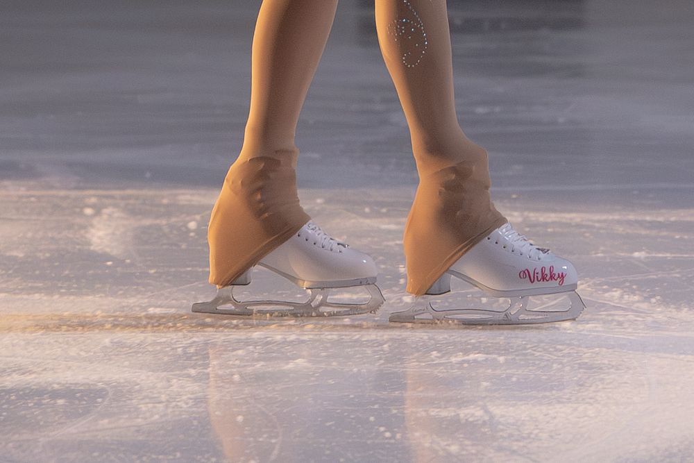 Close-up of white figure skates on ice with warm golden sunlight reflecting off the surface. Hagerstown, Maryland.