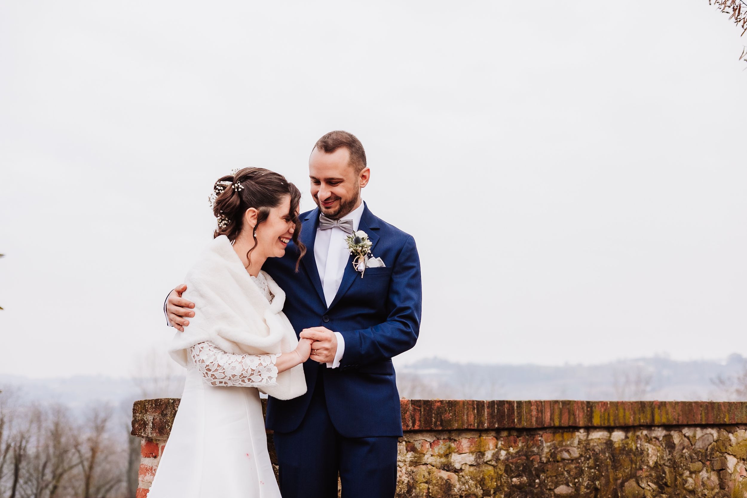 Bride and groom sharing a tender moment outdoors on their wedding day, with a scenic winter landscape backdrop.