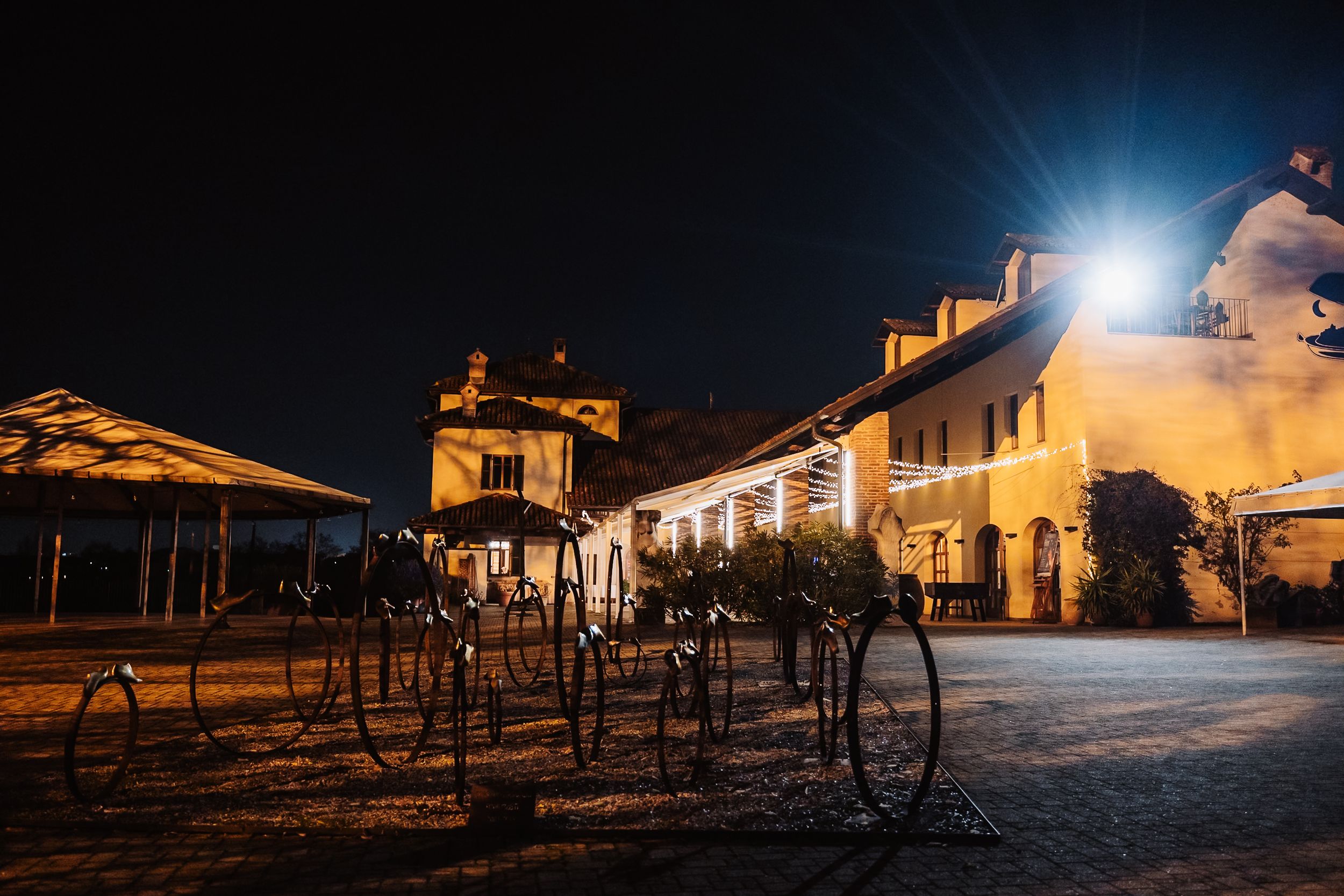 Illuminated historic building and bicycle rack at night with warm golden lights creating an atmospheric outdoor scene.