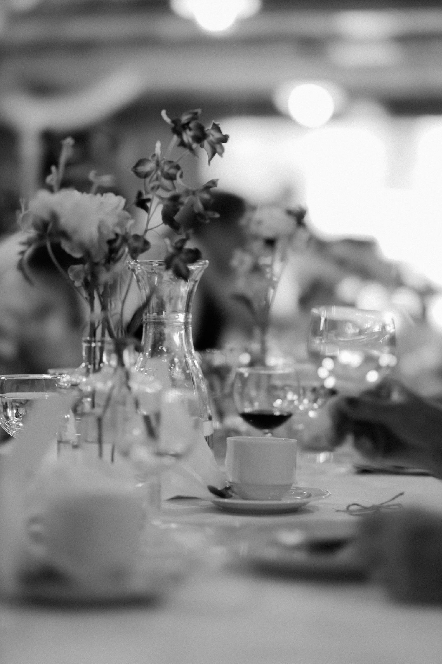 Black and white photo of an elegant banquet table set with floral centerpieces, wine glasses, and fine china.
