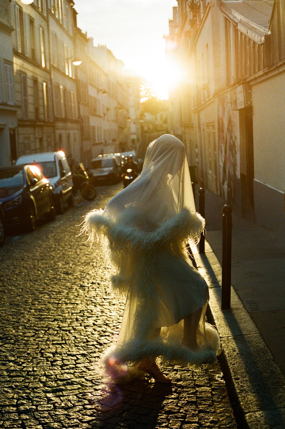 Bride n a fluffy feather dress cobblestone streets bathed in golden sunset light in Paris. Montmartre fashion wedding photos. film