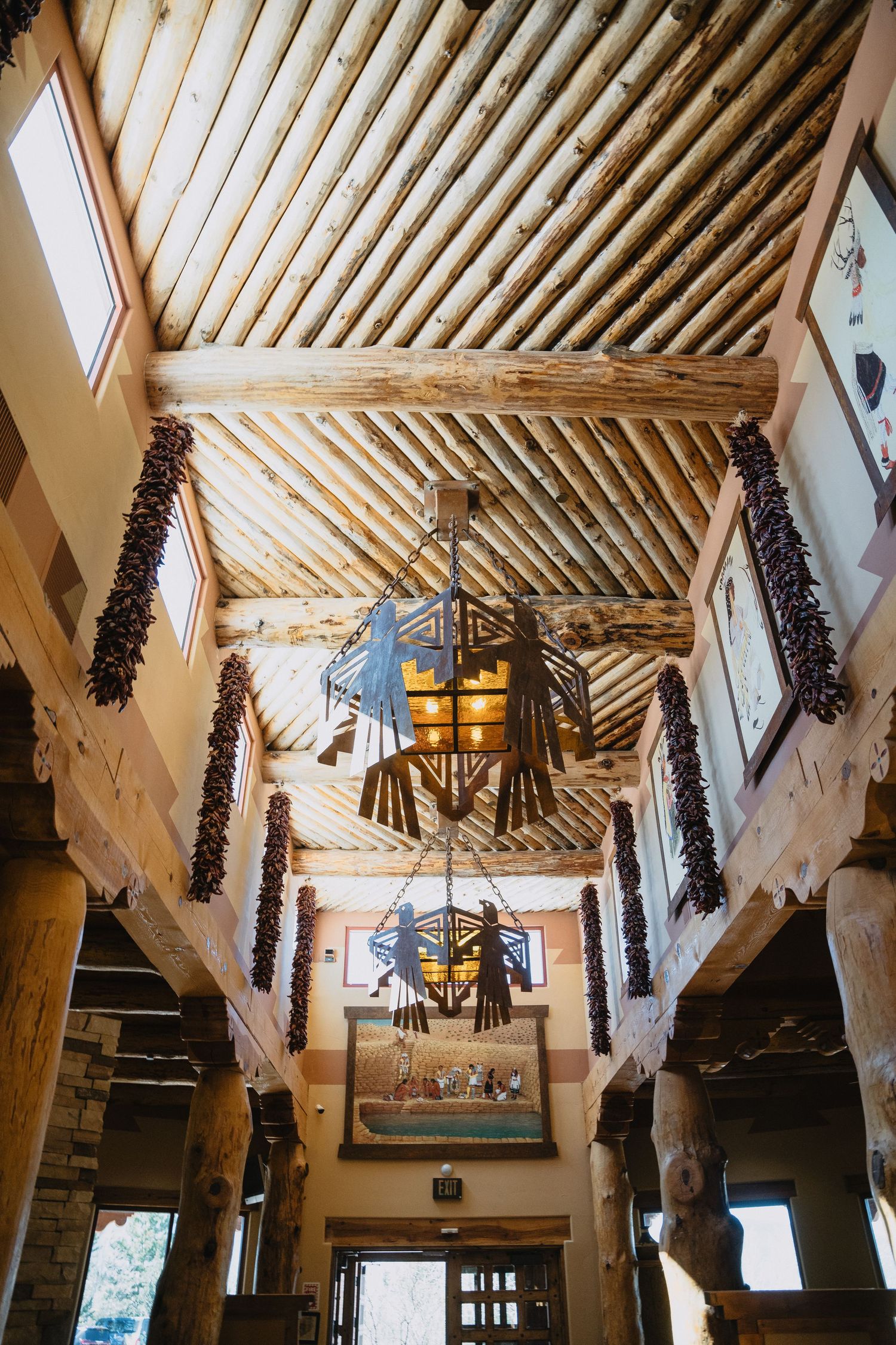Rustic lodge interior with log beam ceiling, hanging dried chili ristras, and decorative chandelier at Nature Pointe venue