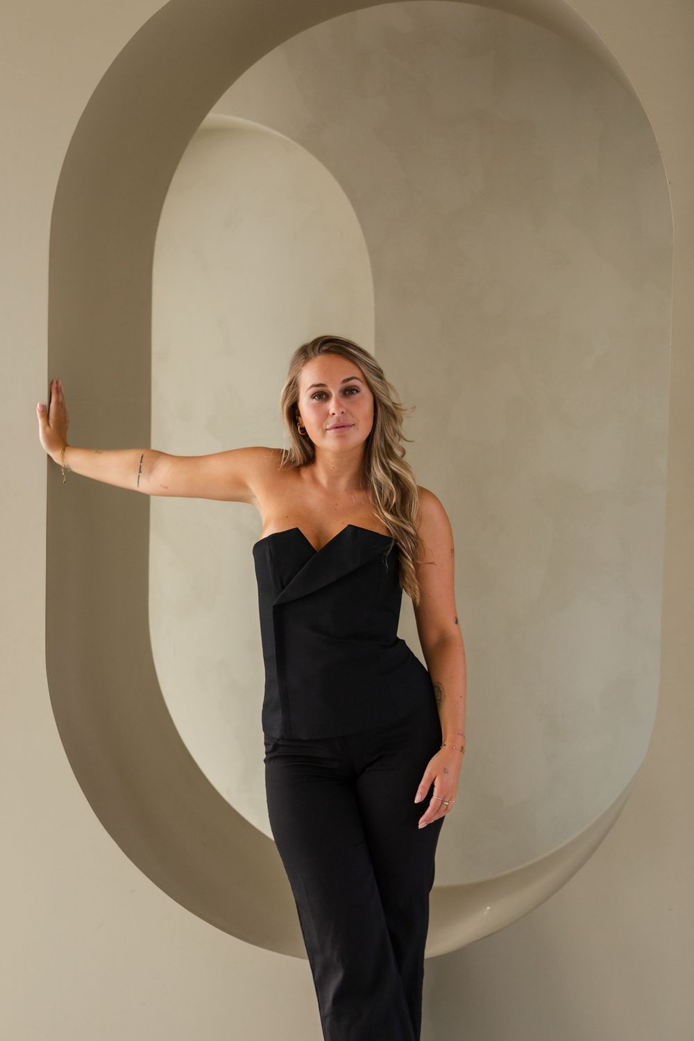 A sequence of artistic poses in black attire against an architectural backdrop with curved archways.