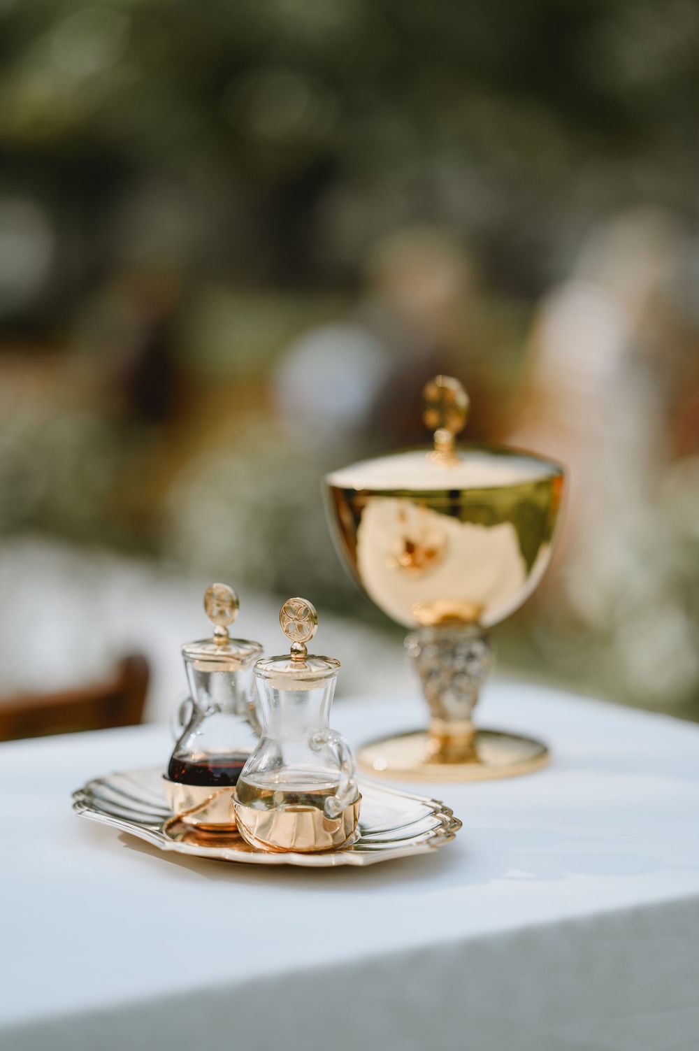 Gold chalice and crystal cruets on silver tray arranged on white linen table for Catholic wedding Mass.