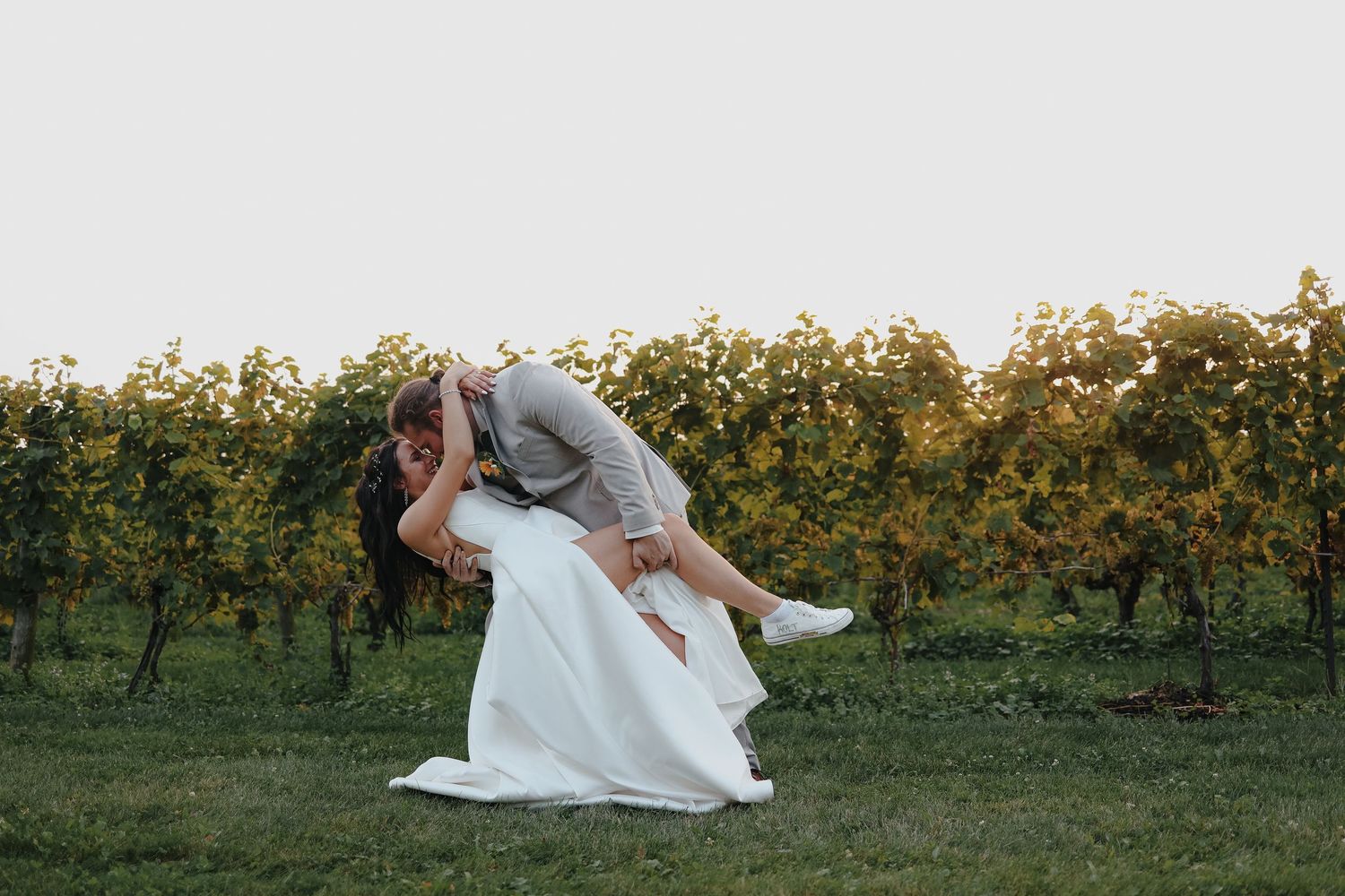 A silhouetted couple kissing with sun flare and mountain lake backdrop.