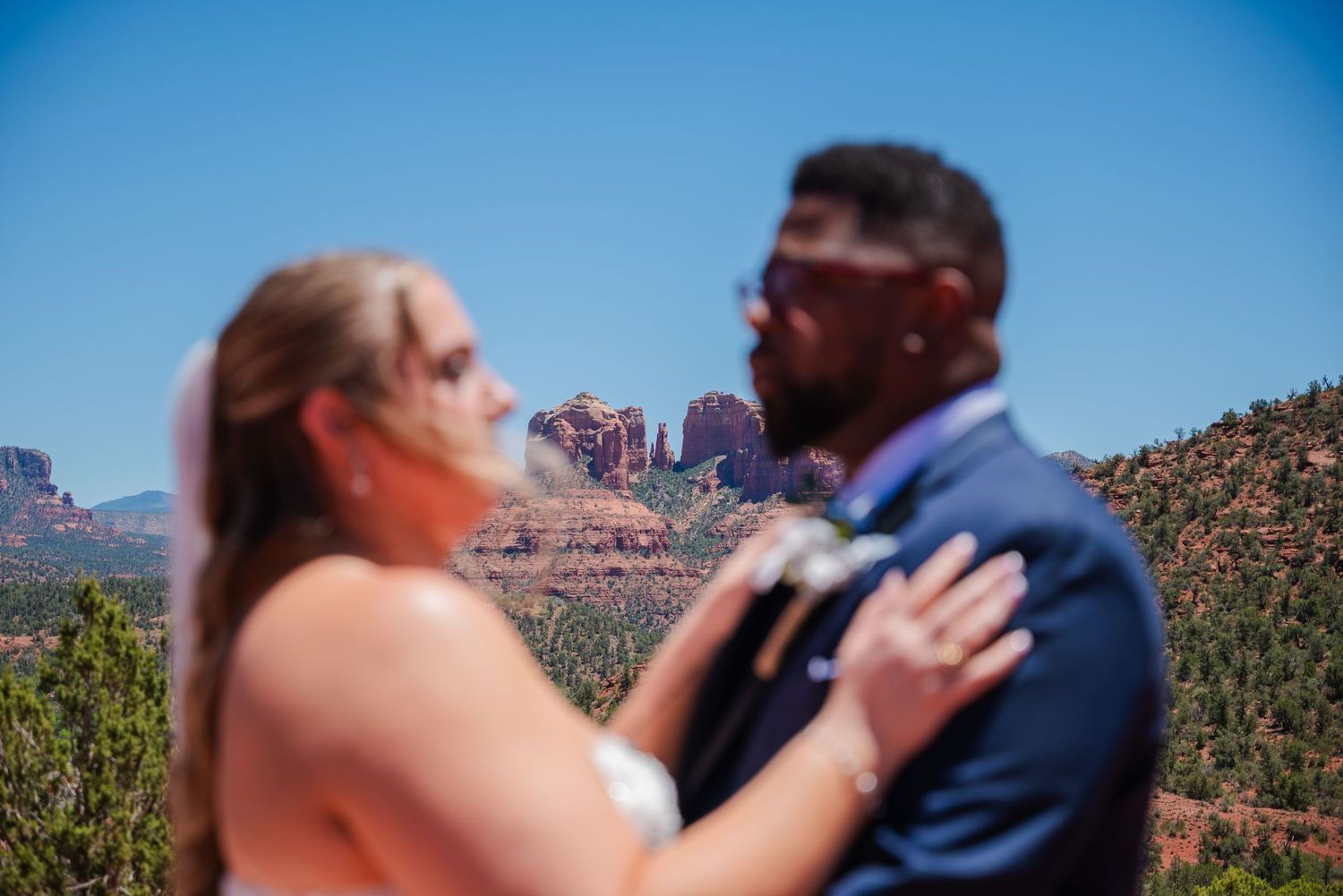 Couple sharing a romantic moment at their Sedona wedding with iconic red rock formations in the background.