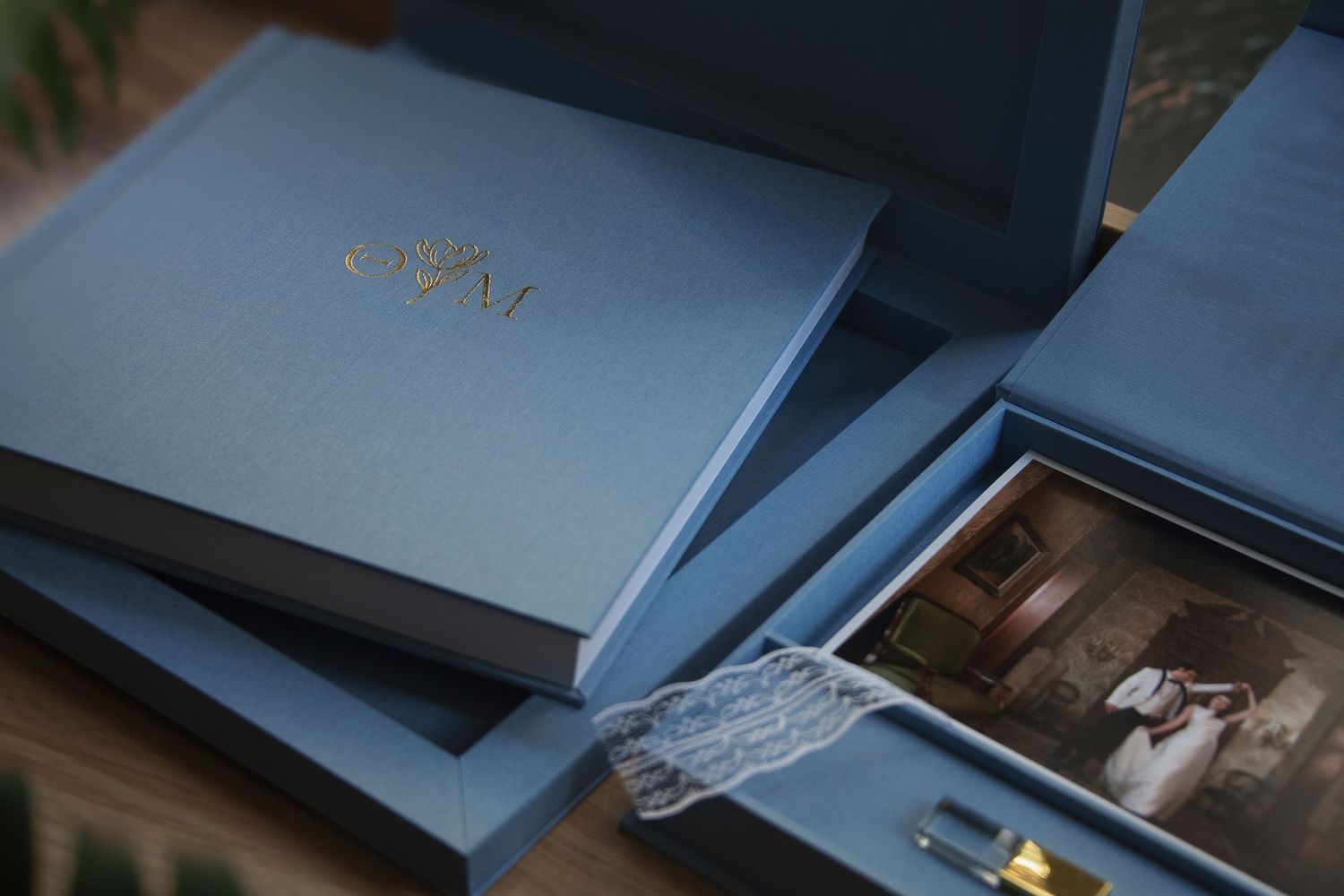 Premium wedding album package including a luxury linen photo book with gold foil monogram and a matching presentation box.
