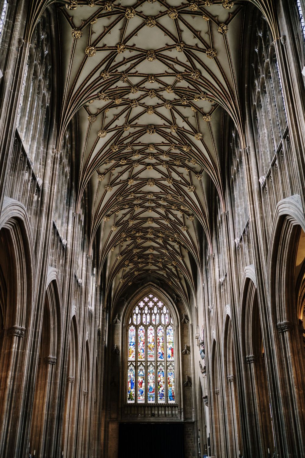 St Mary Redcliffe Church, Bristol Wedding. intricate fan vaulted ceiling, stone arches, and colorful stained glass window at the far end.