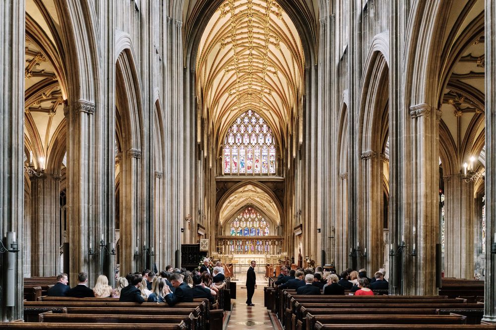 St Mary Redcliffe Church, Bristol Wedding with ornate vaulted ceiling, stained glass windows, and guests seated in wooden pews.