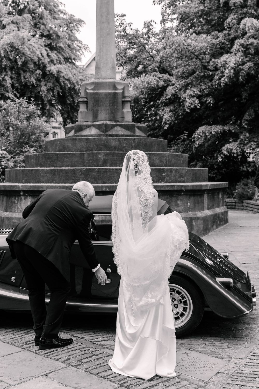 Black and white photo of a bride in lace veil standing outside St Mary Redcliffe Church, Bristol Wedding