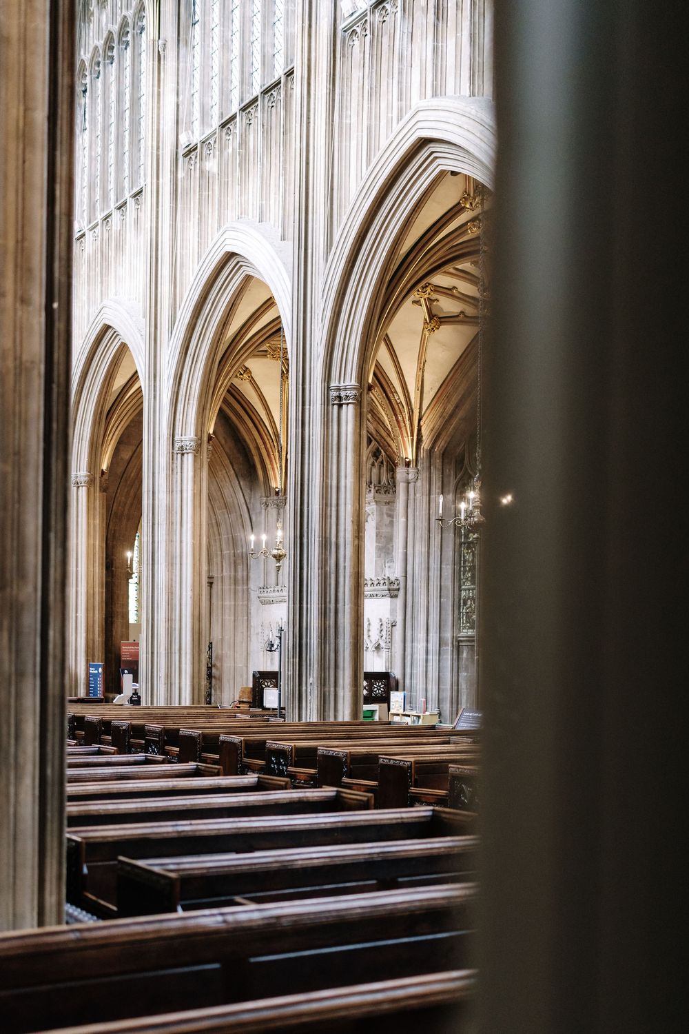 St Mary Redcliffe Church, Bristol. Soaring stone arches, wooden pews, and ornate vaulted ceilings viewed through a doorway.