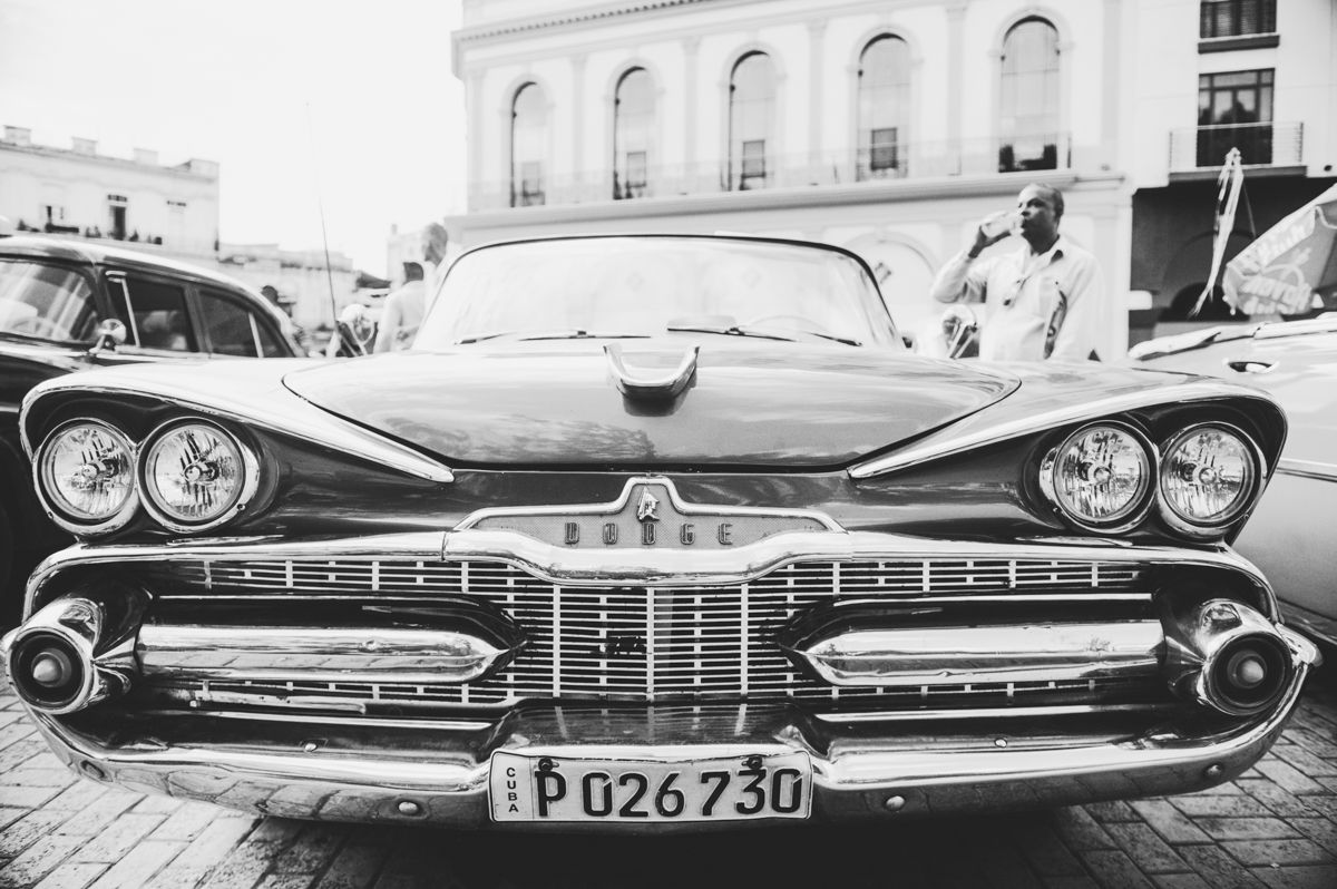 Black and white photo of a classic vintage American car with license plate P026730 parked on a cobblestone street.