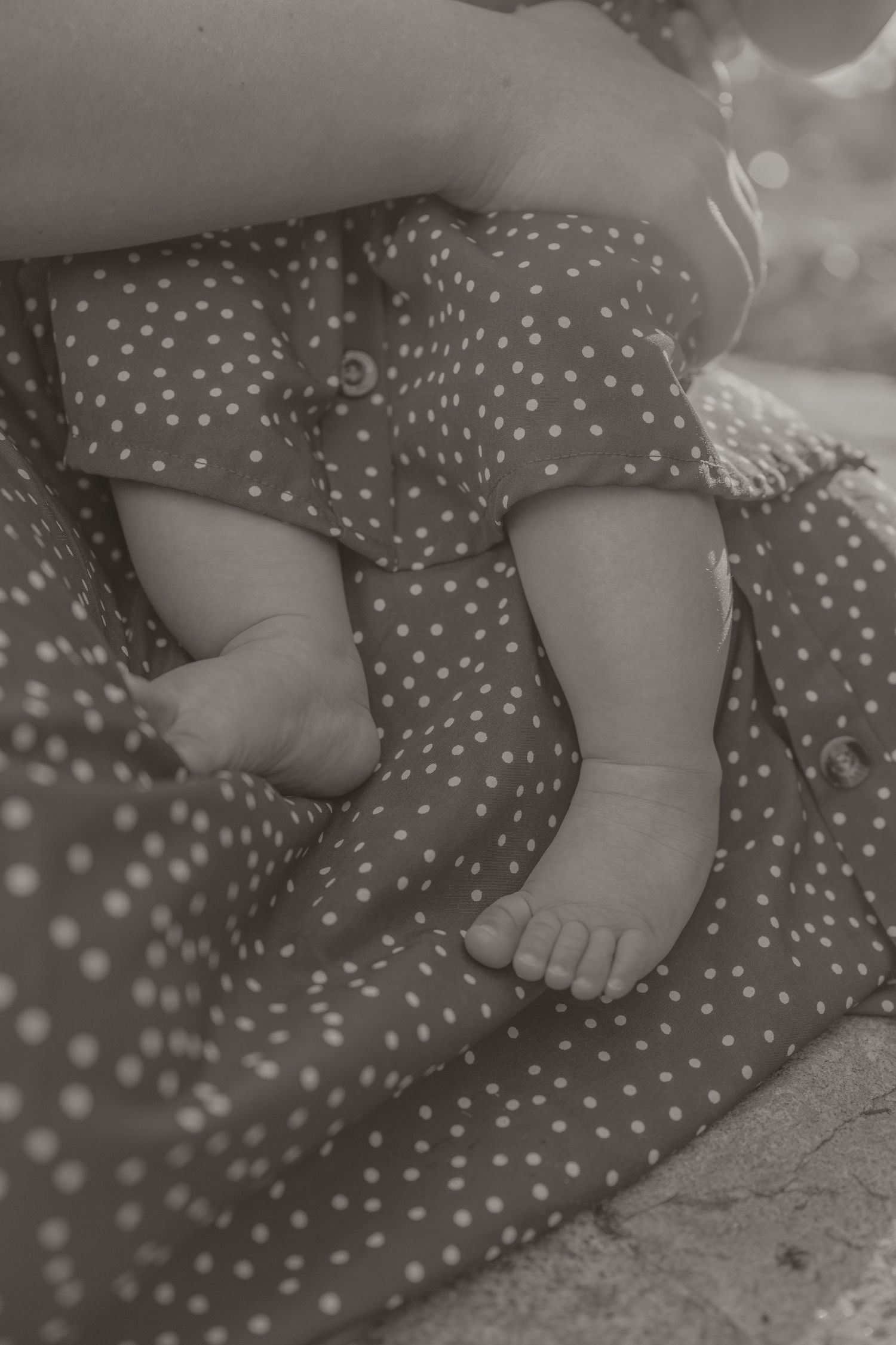 Black and white family portrait of smiling parents holding their toddler daughter outdoors in a backyard.