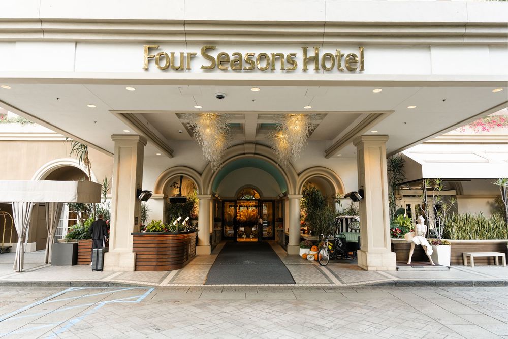 Grand entrance of Four Seasons Hotel featuring arched doorways, elegant lighting, and lush greenery.