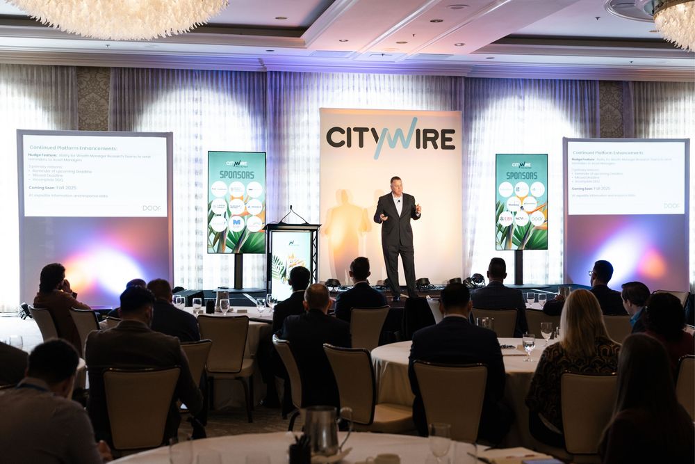 Speaker presenting at a Citywire financial conference in an elegant ballroom with attendees seated at round tables.
